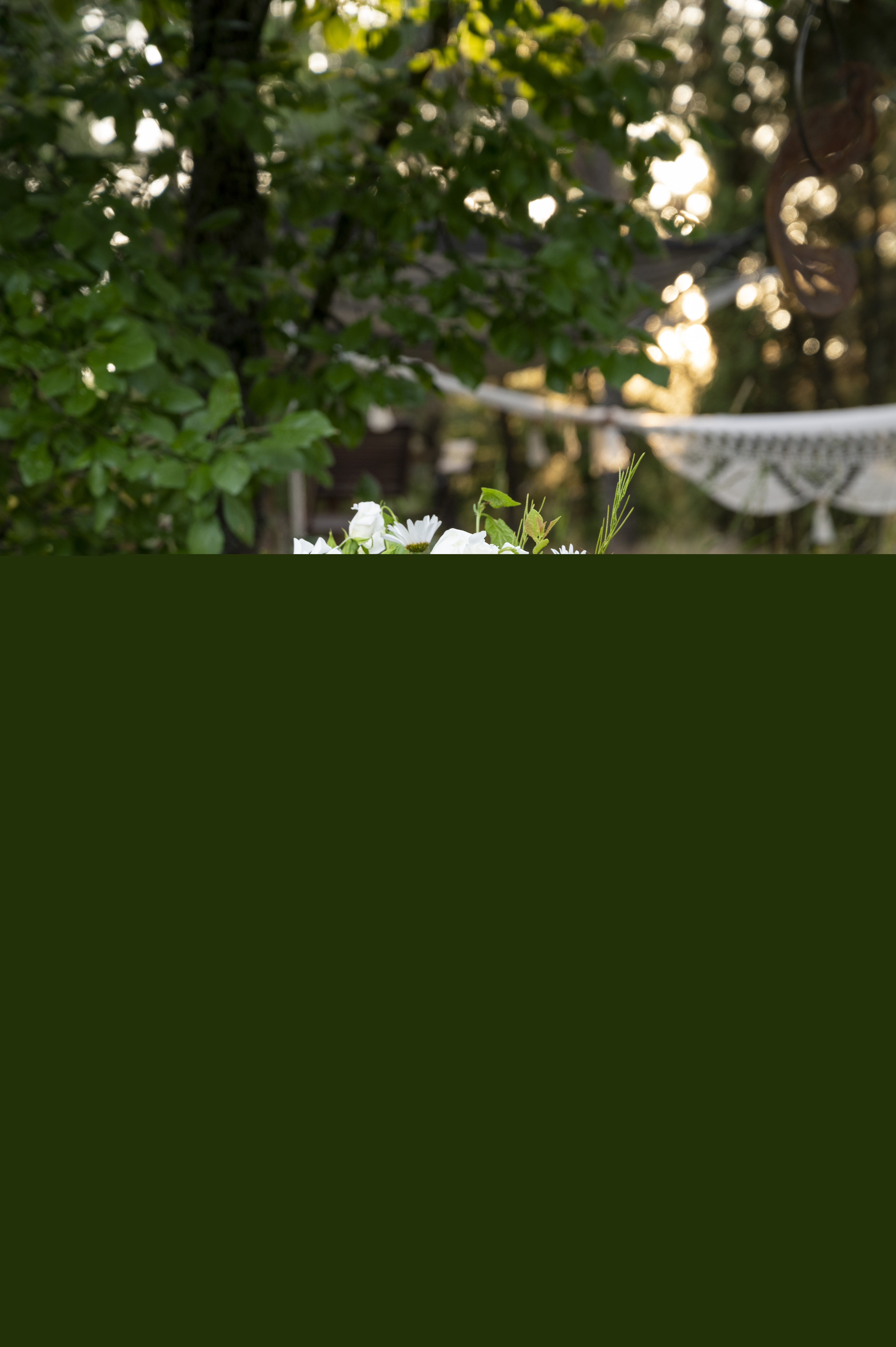 En vas med sommarblommor står på ett bord i trädgården.