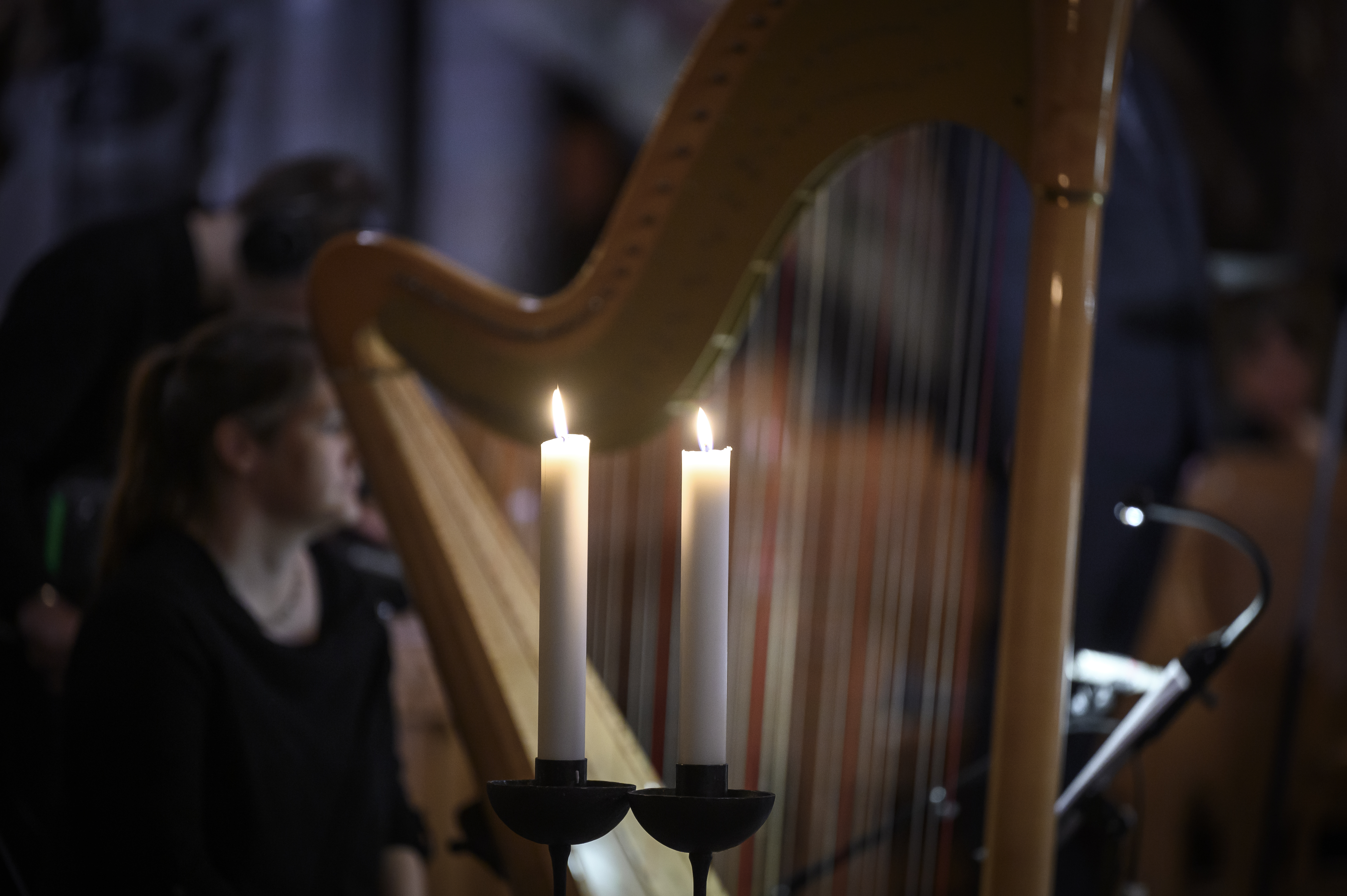 Två tända stearinljus framför en harpa.