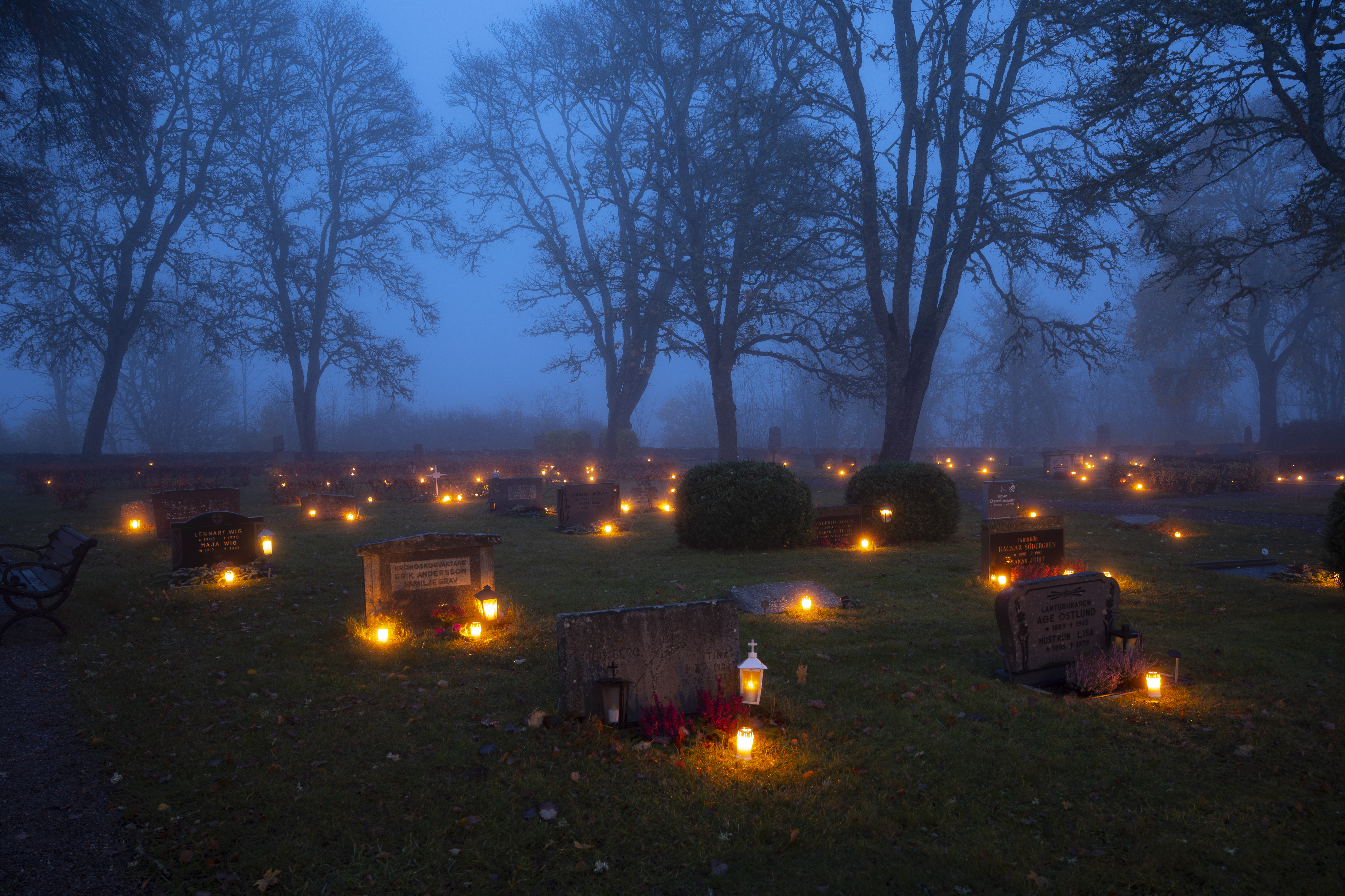 Ljuslyktor lyser på en kyrkogård.