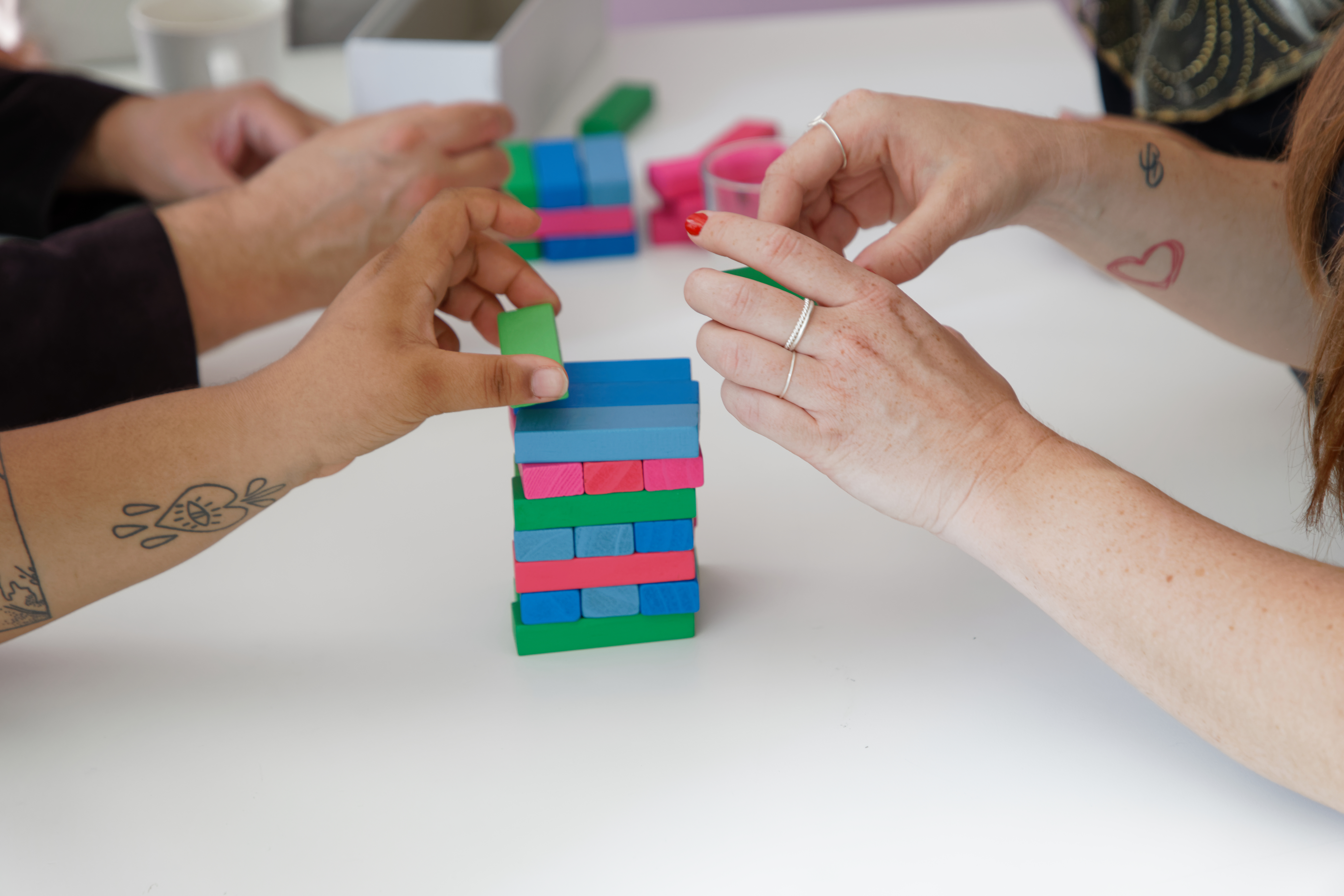 Några personer spelar Jenga med färggranna klossar.