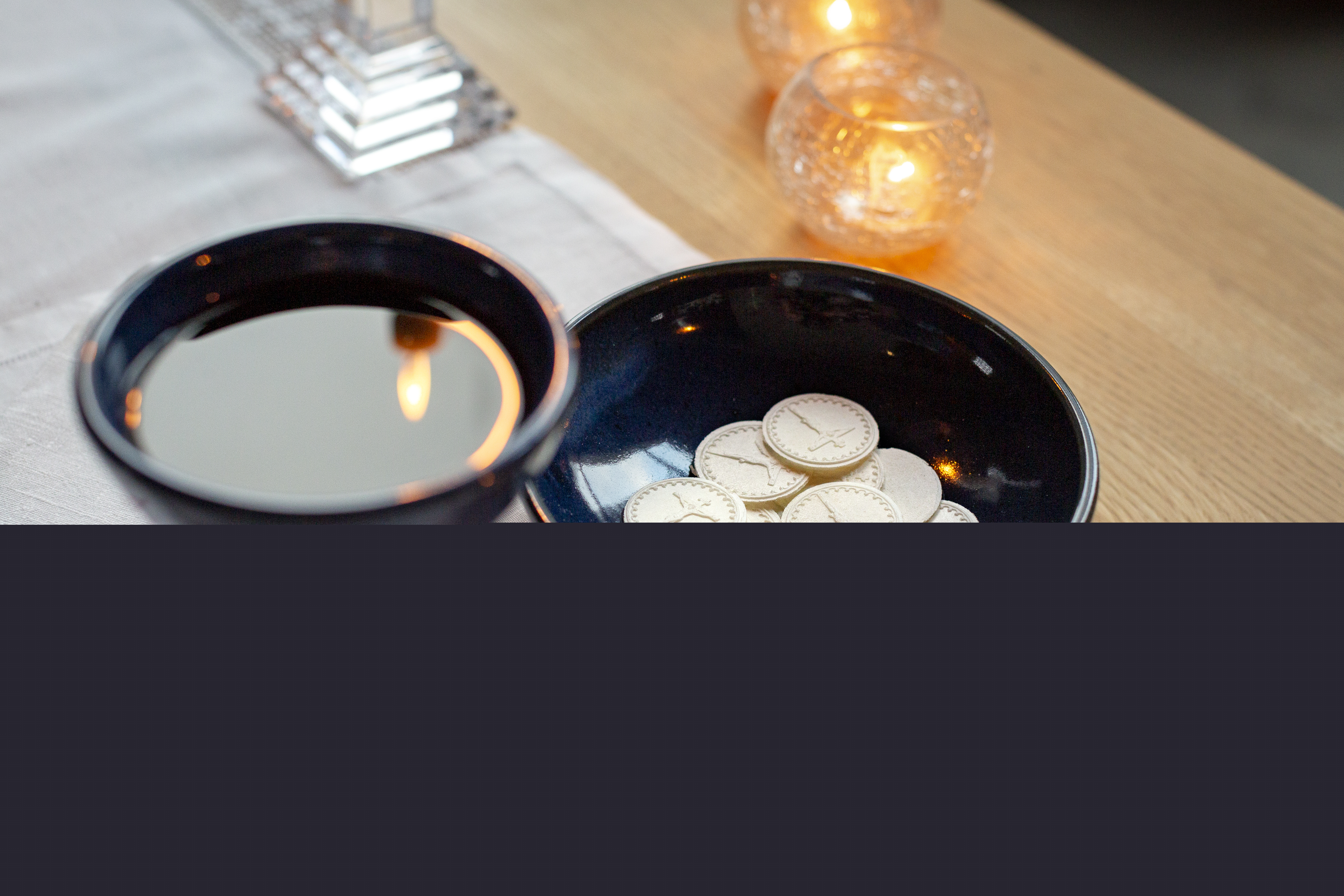 En nattvardskalk med vin och ett fat med oblater står på altaret.