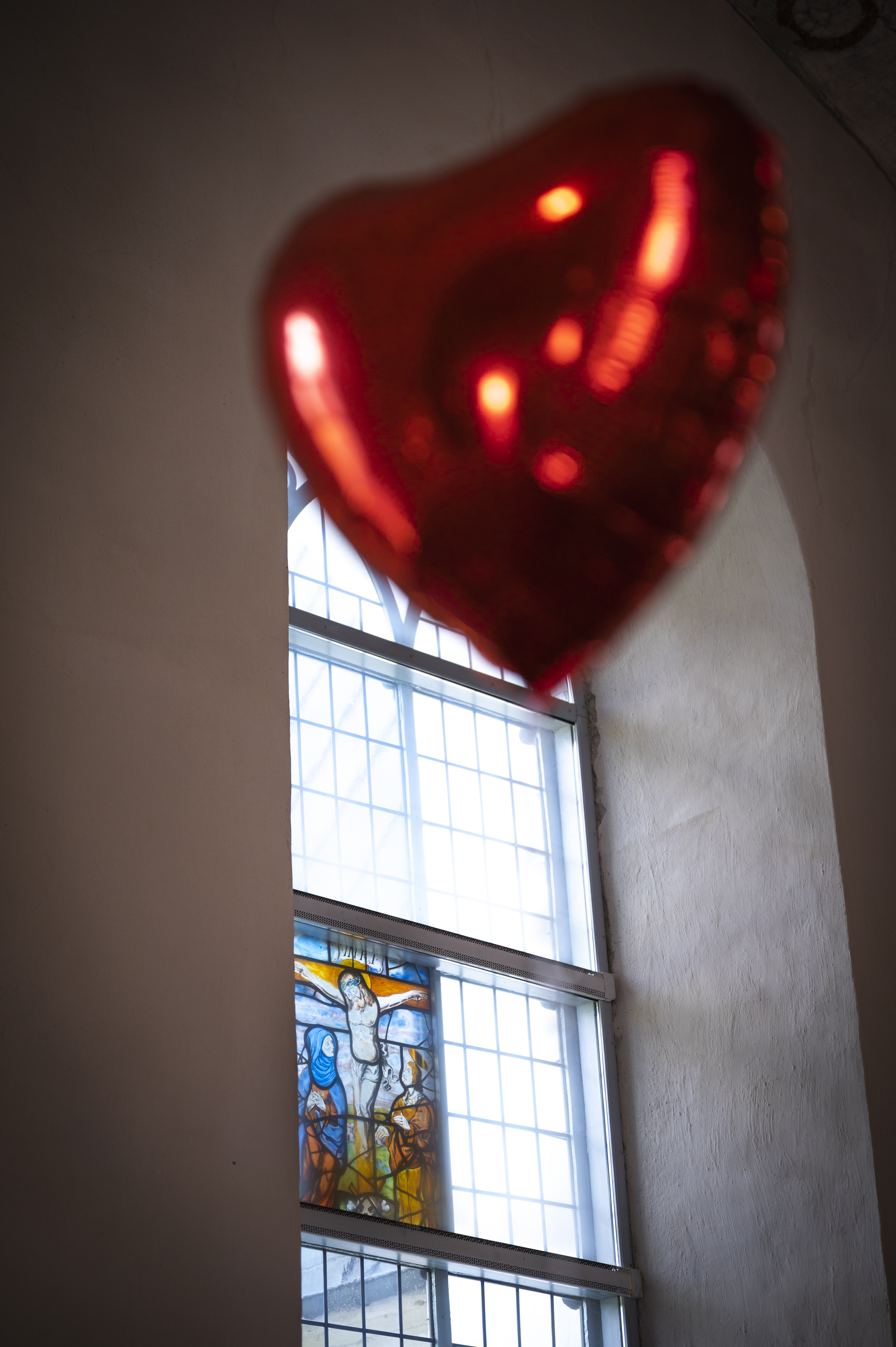 En röd, hjärtformad heliumballong inne i en kyrka.