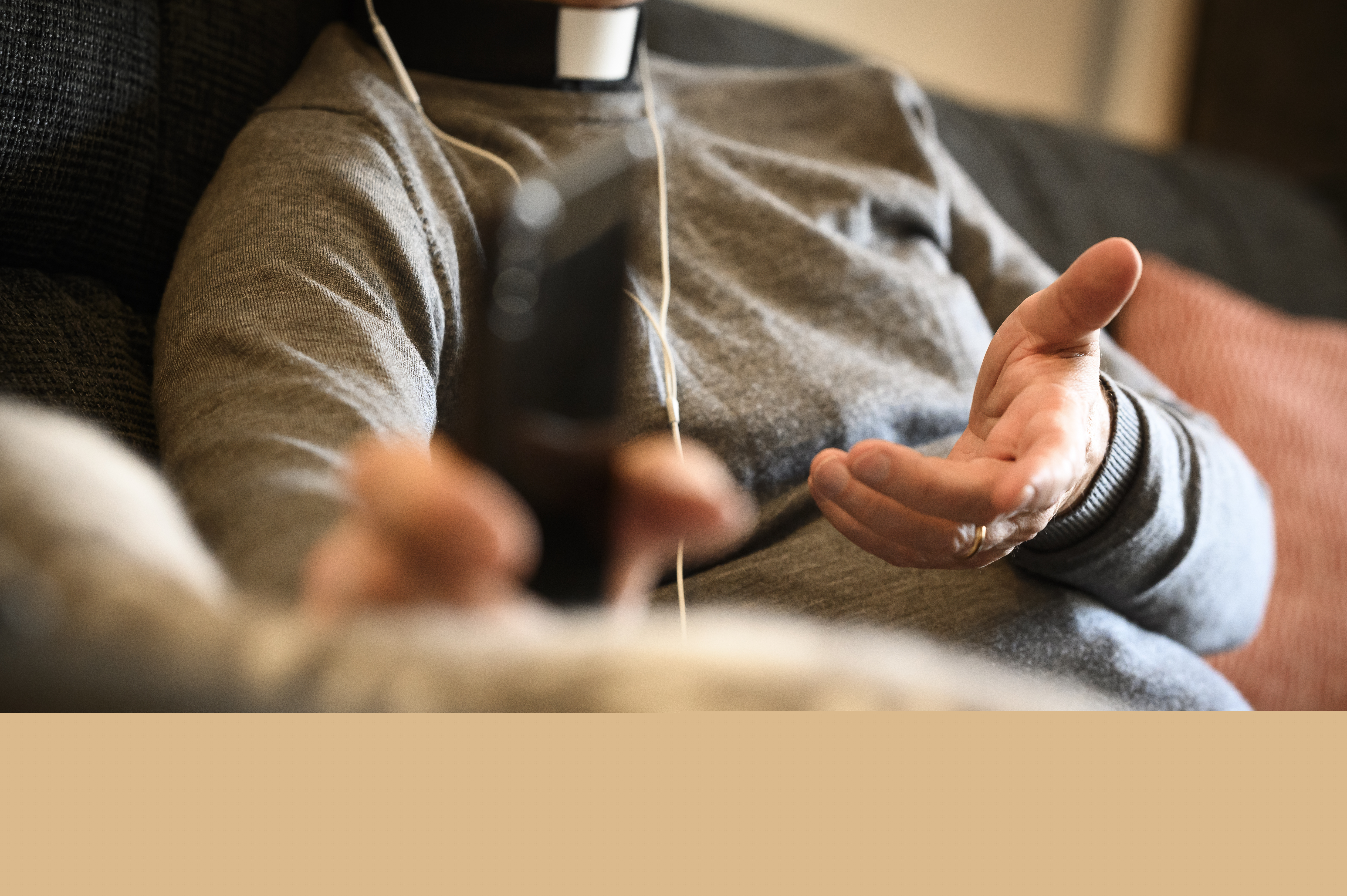 En präst sitter med hörlurar och pratar i mobiltelefon.