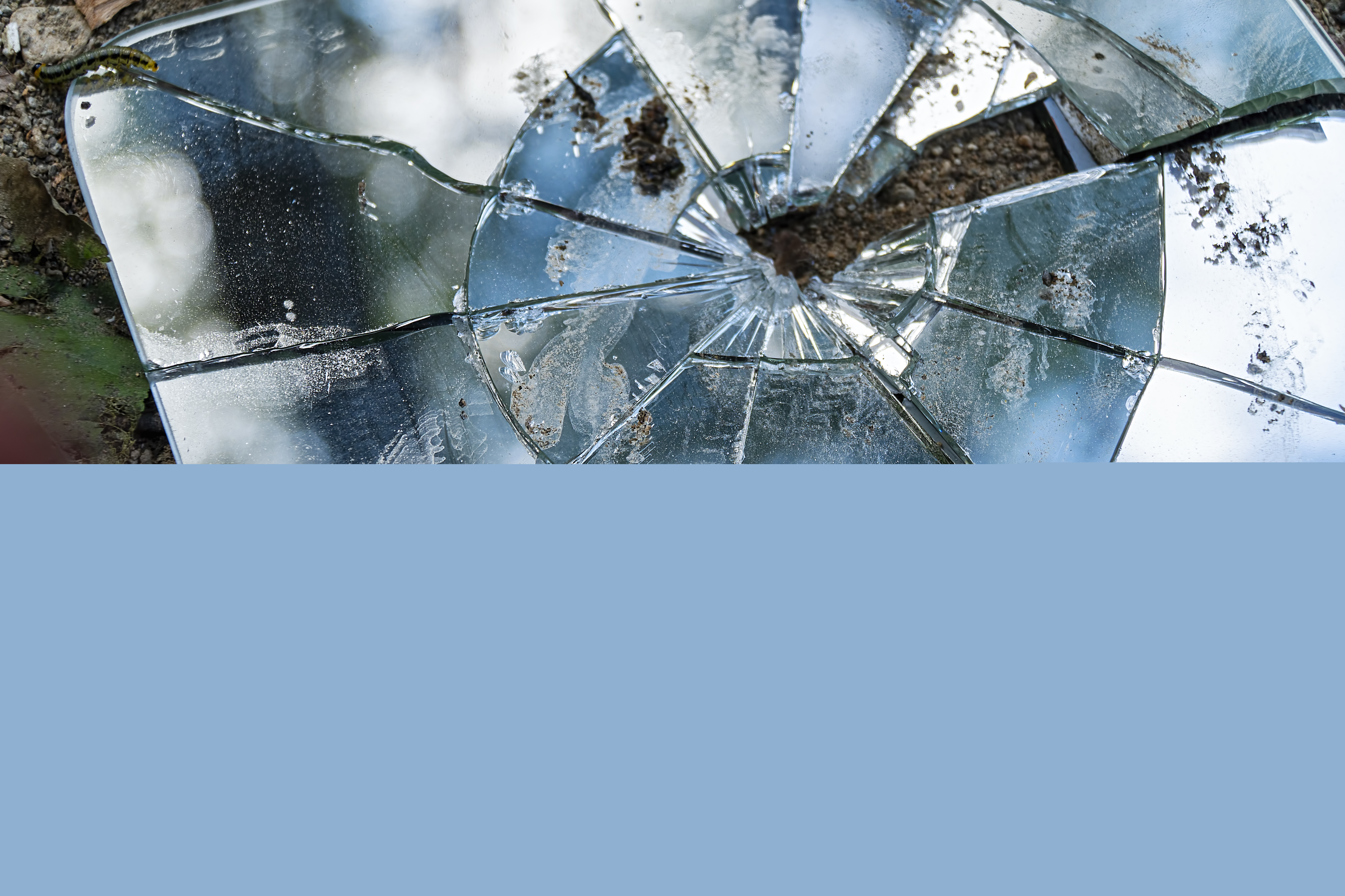 En trasig väggspegel ligger på marken.