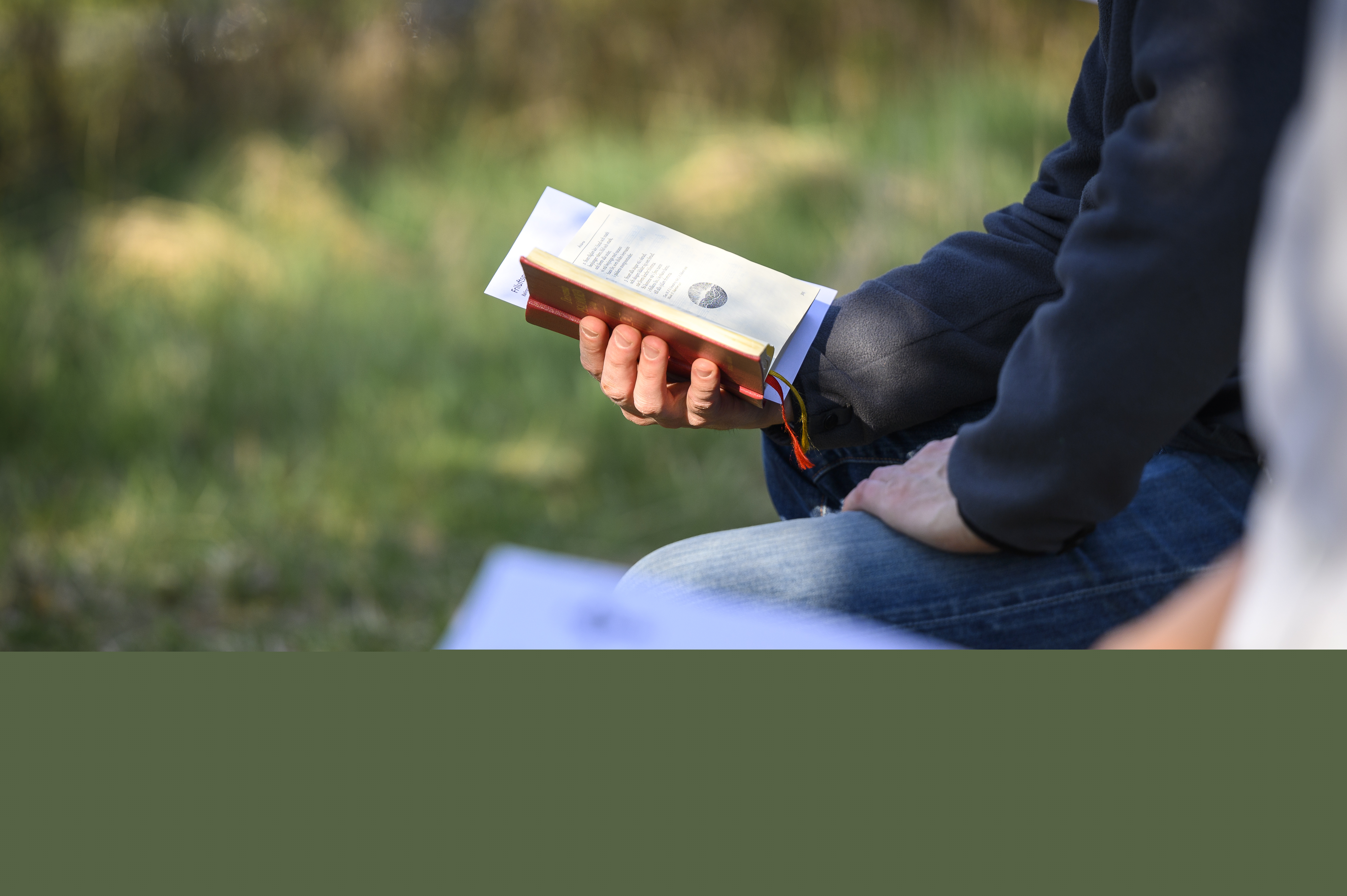 Två personer sitter bredvid varandra utomhus med varsin psalmbok.