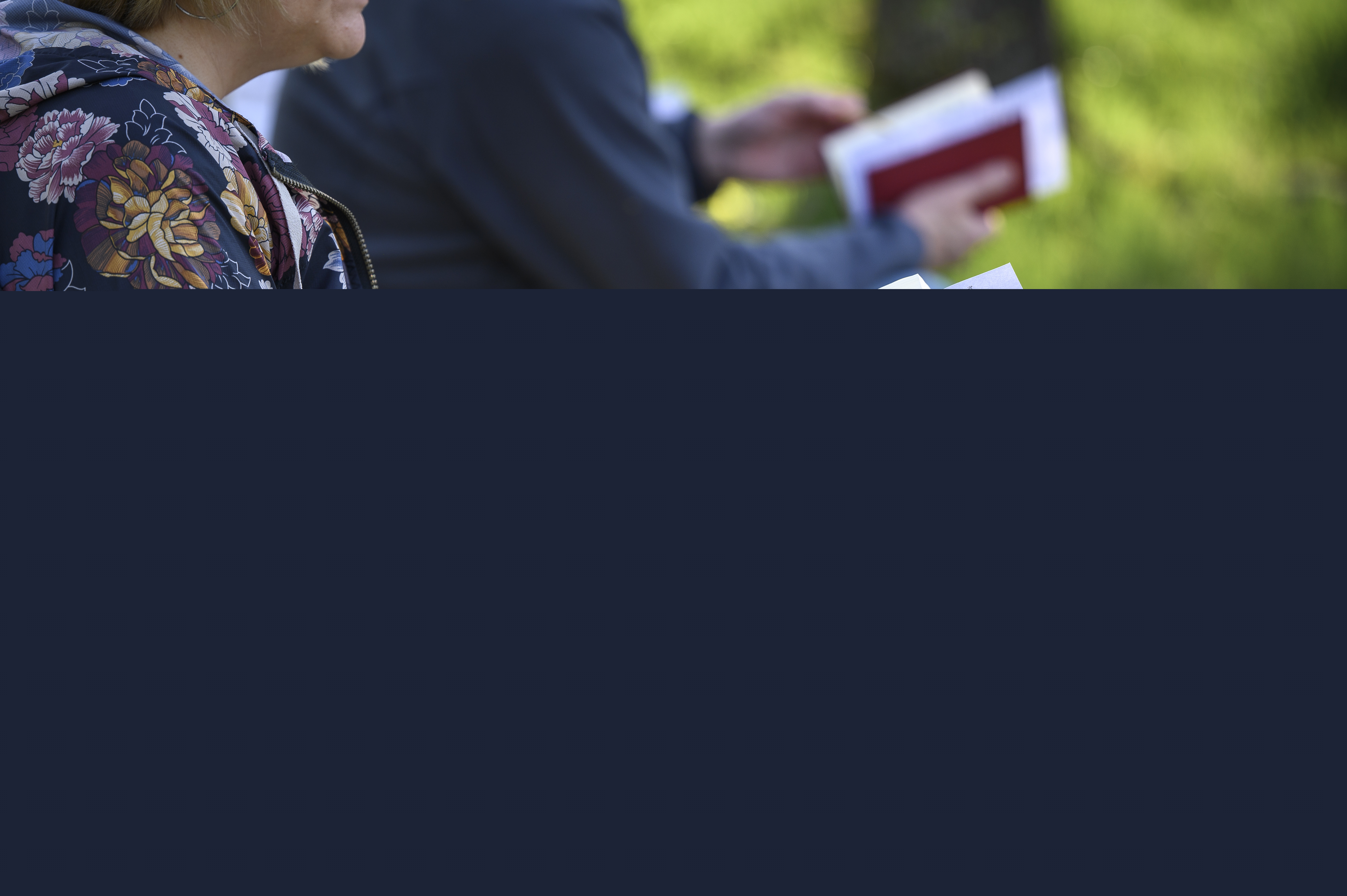 Två personer sitter bredvid varandra utomhus med varsin psalmbok.