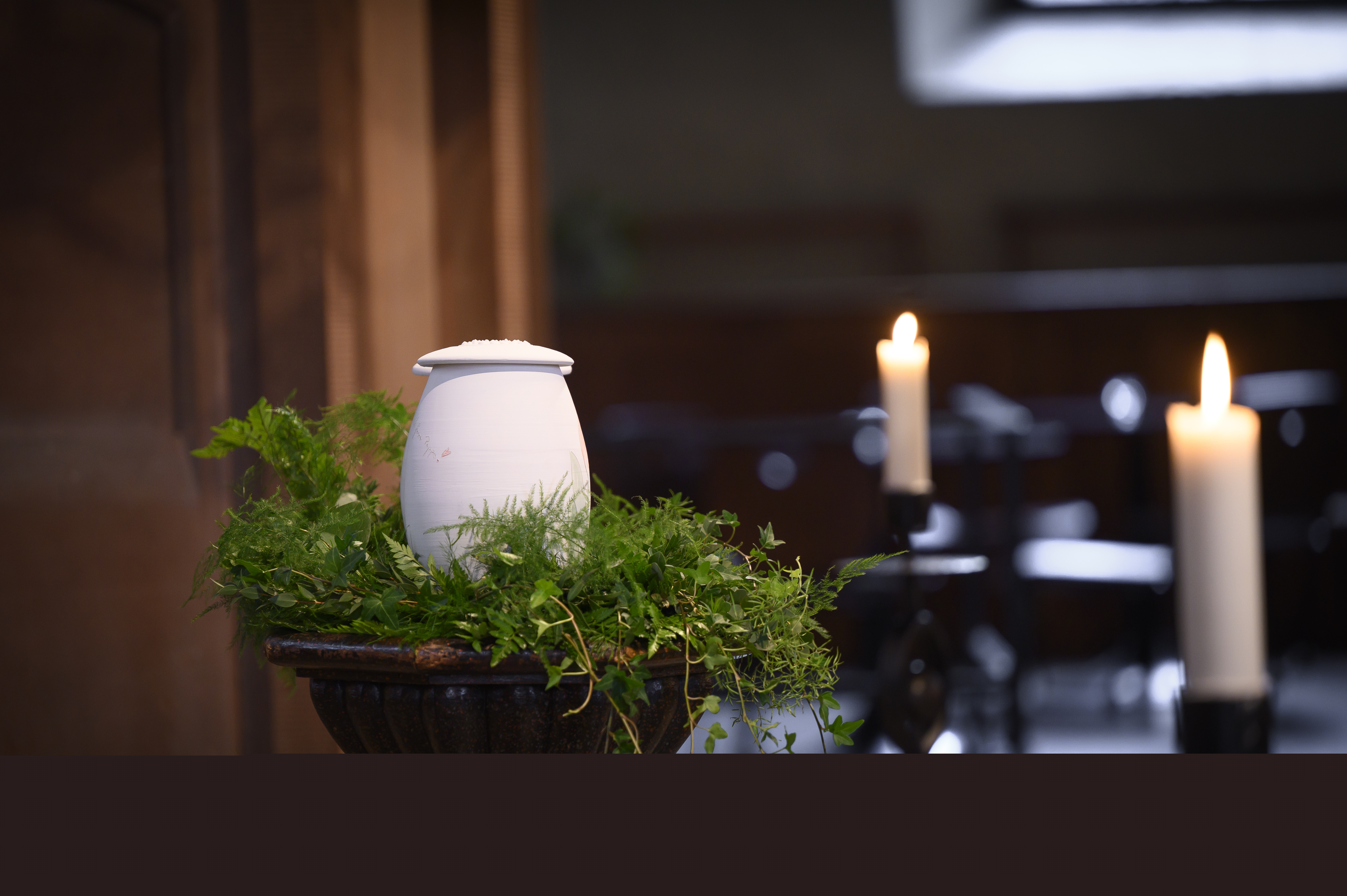 En urna står uppställd bland ormbunksblad i kyrkan.