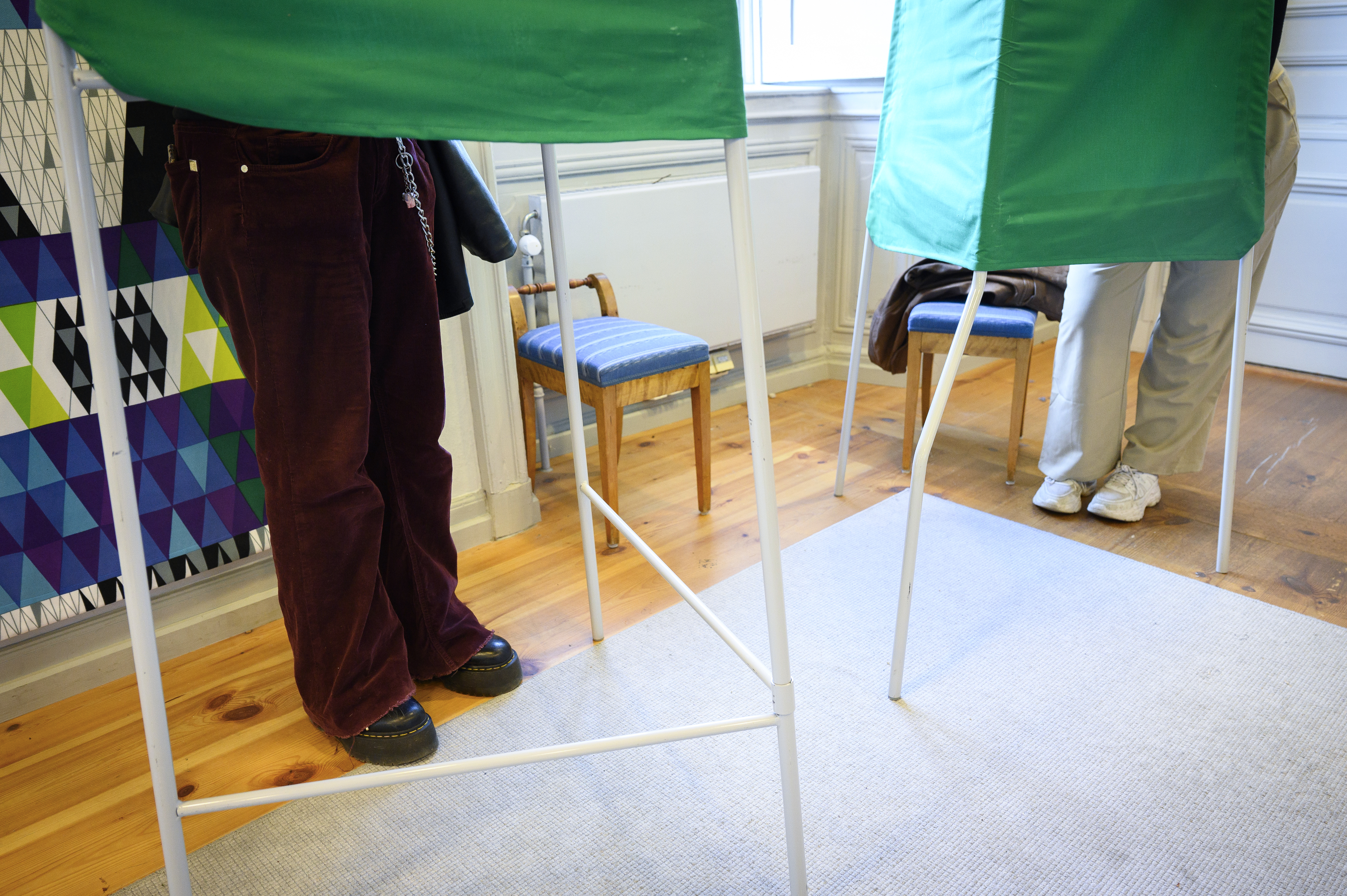 Två personer står i varsitt valbås.