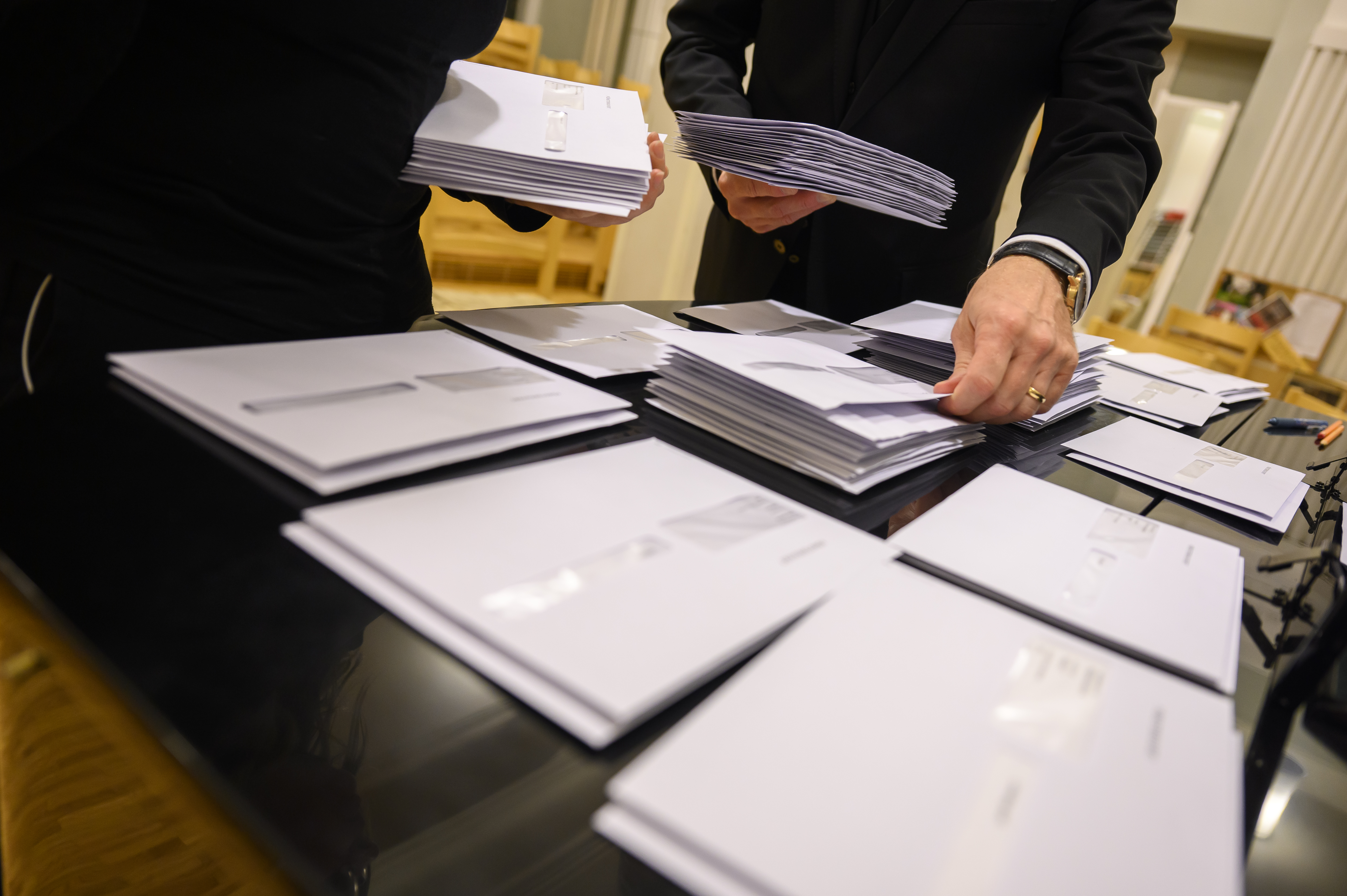 Två personer sorterar kuvert i olika högar.