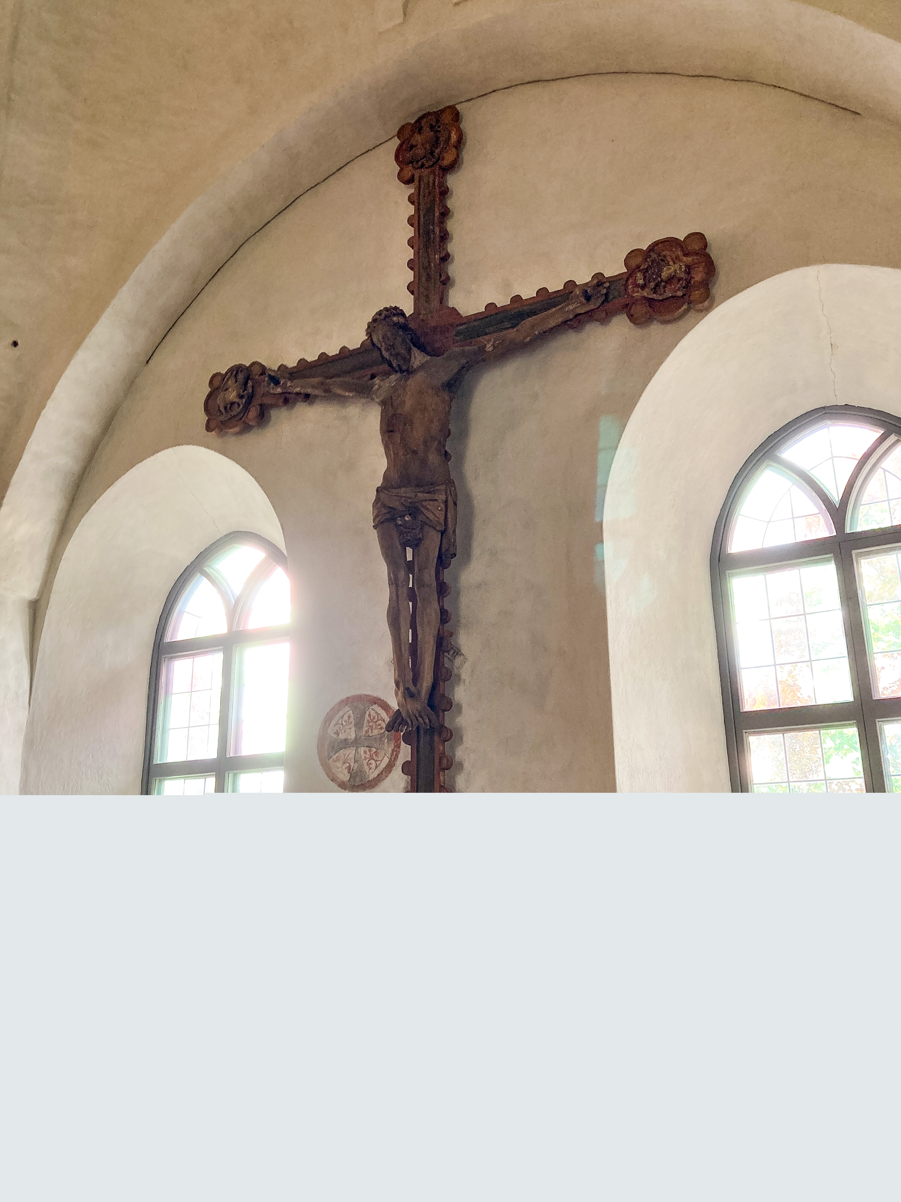 Ett stort krucifix hänger på väggen i en kyrka.