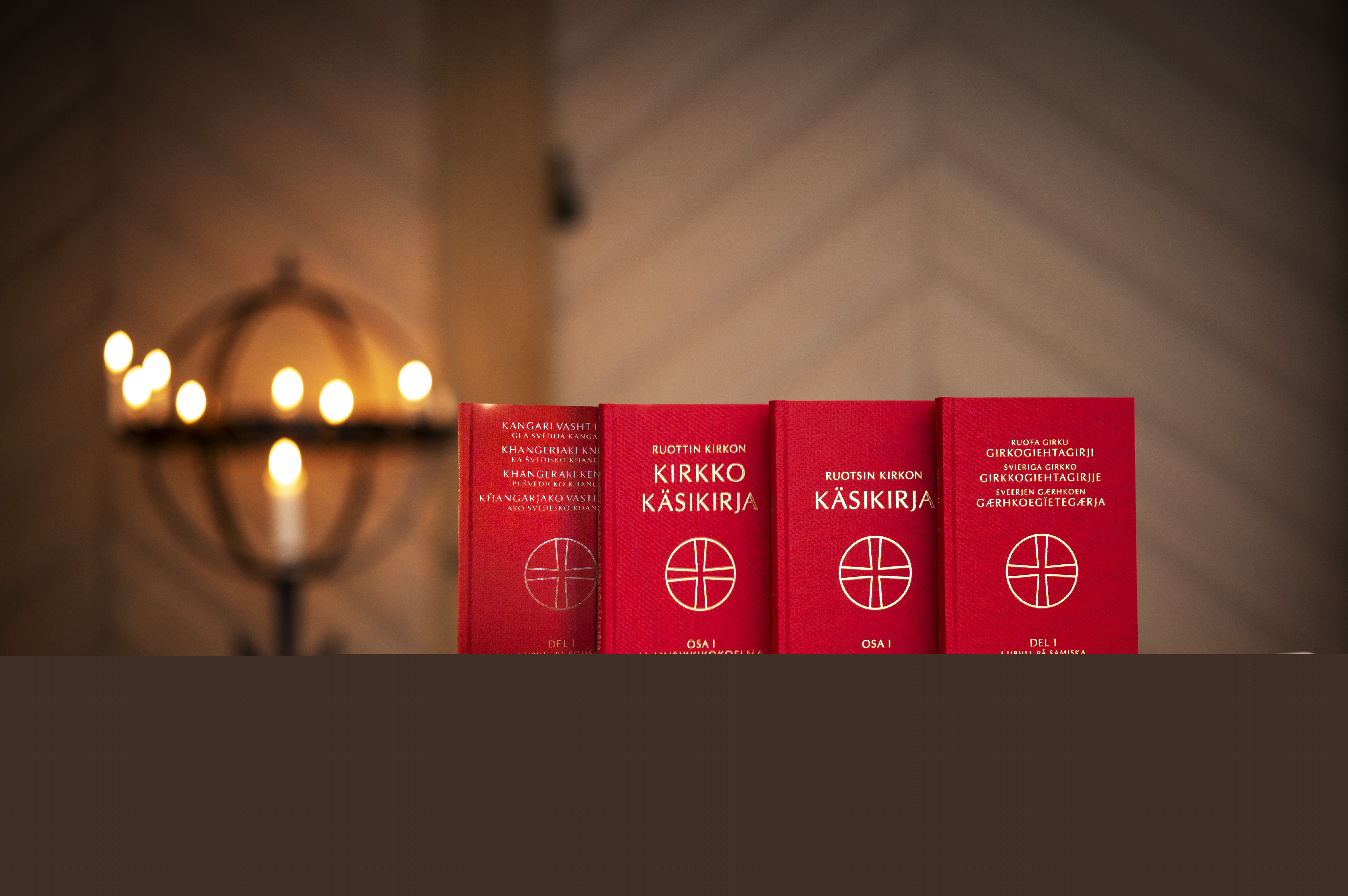 Kyrkohandboken på fyra olika minoritetsspråk står uppställda på ett bord i en kyrka.