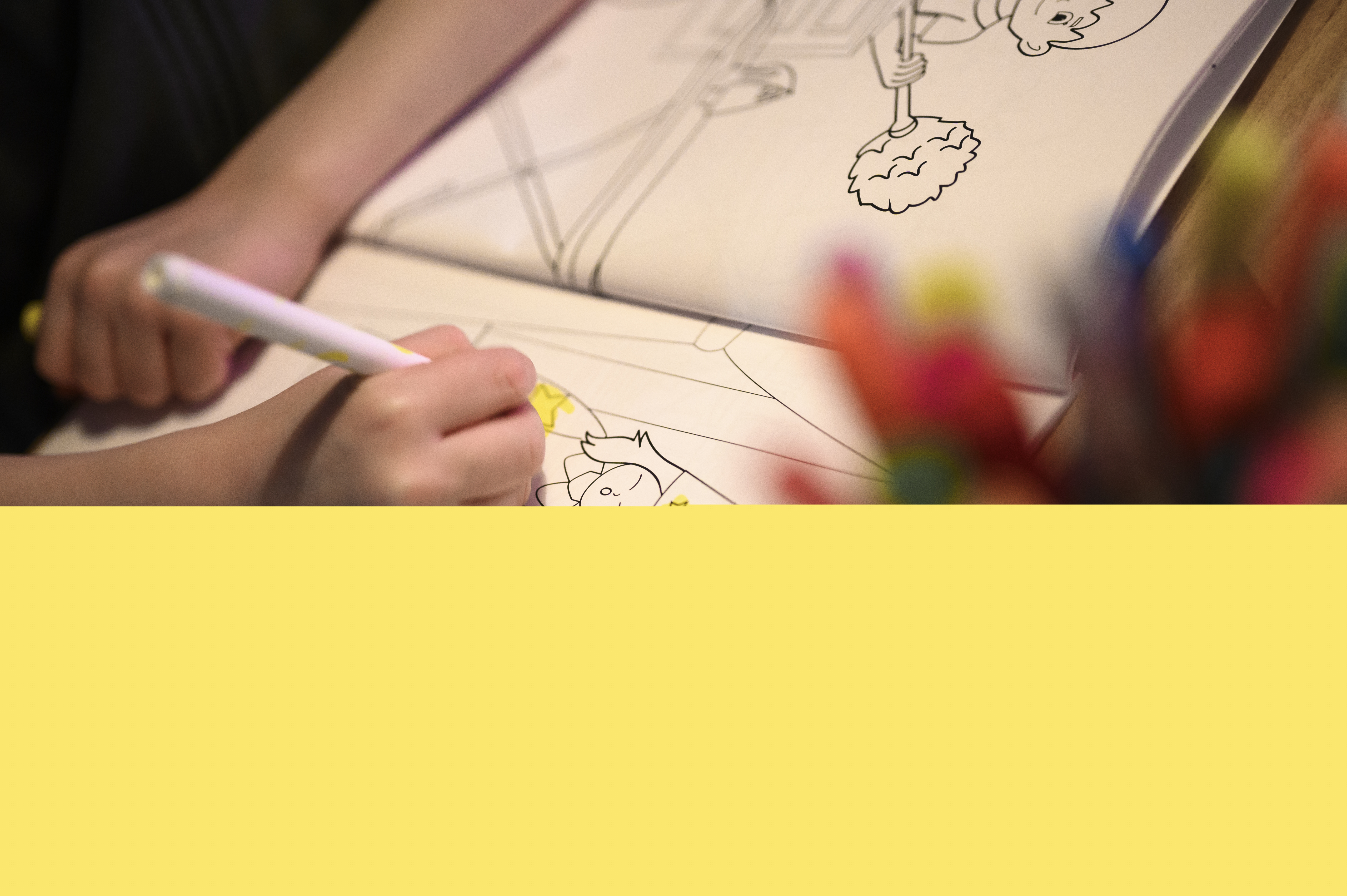 Närbild på ett barn som sitter och färglägger i en målarbok med jultema.