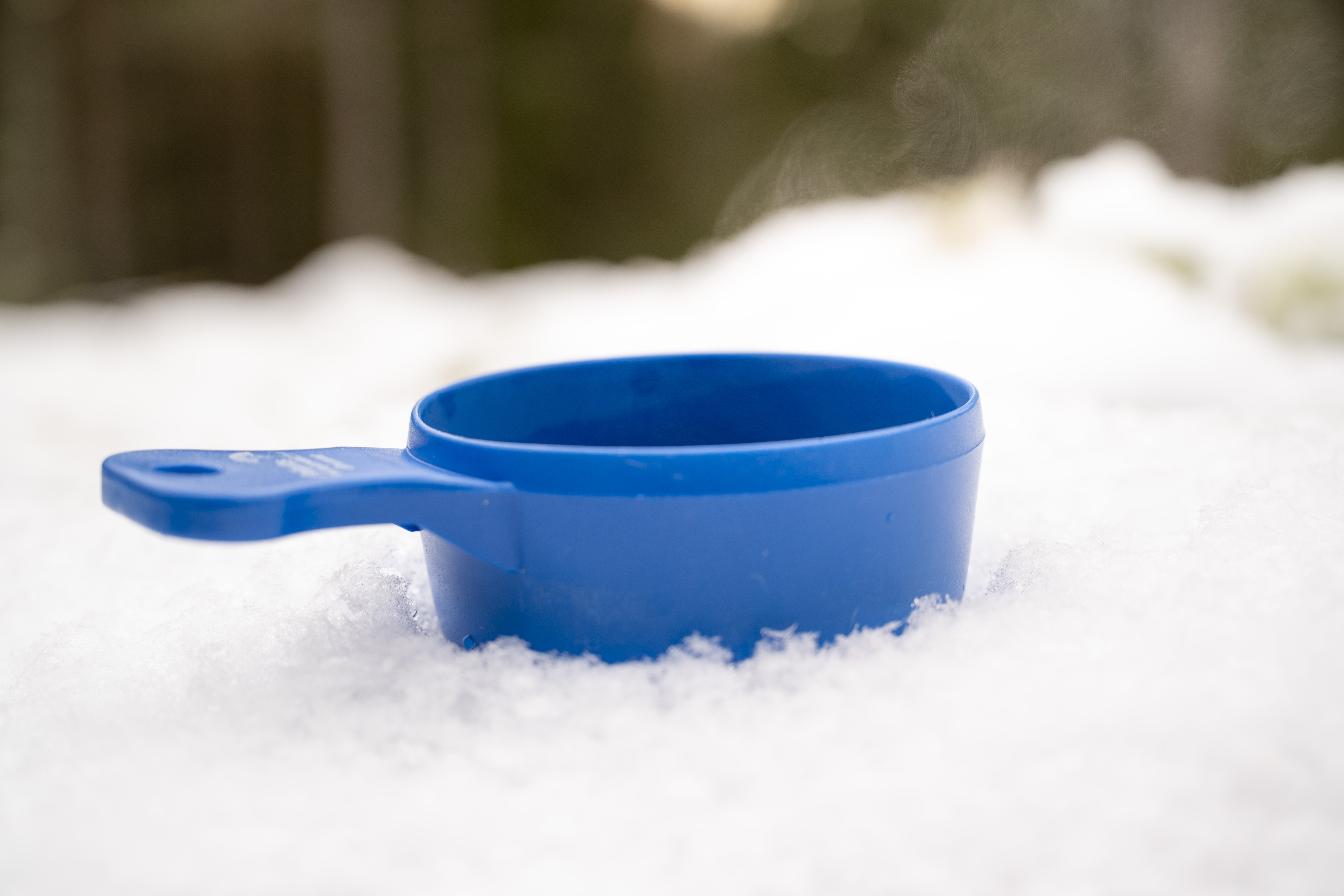 Närbild på en blå kåsa nedtryckt i snön.