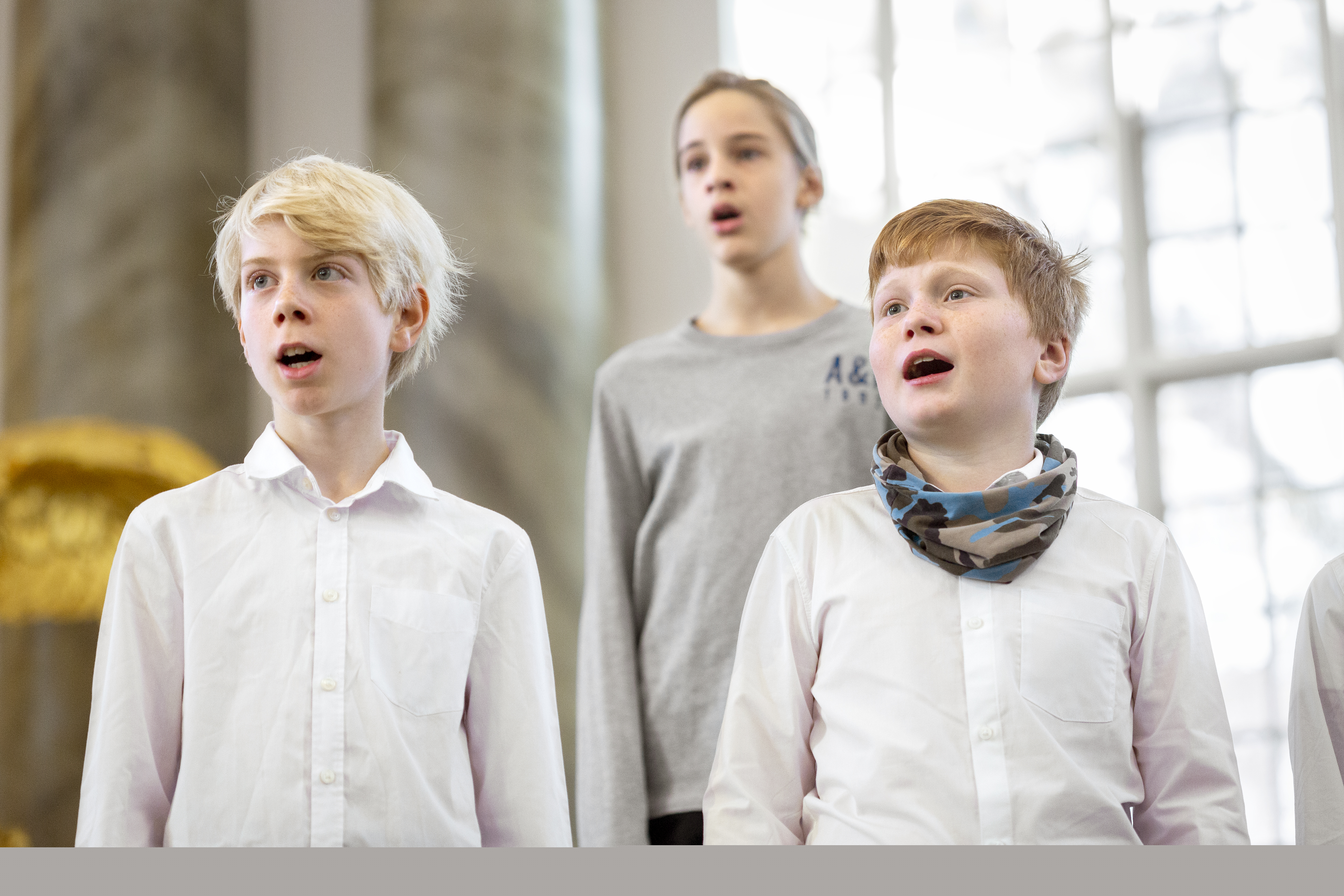 Närbild på medlemmar i en barnkör som sjunger i en kyrka.