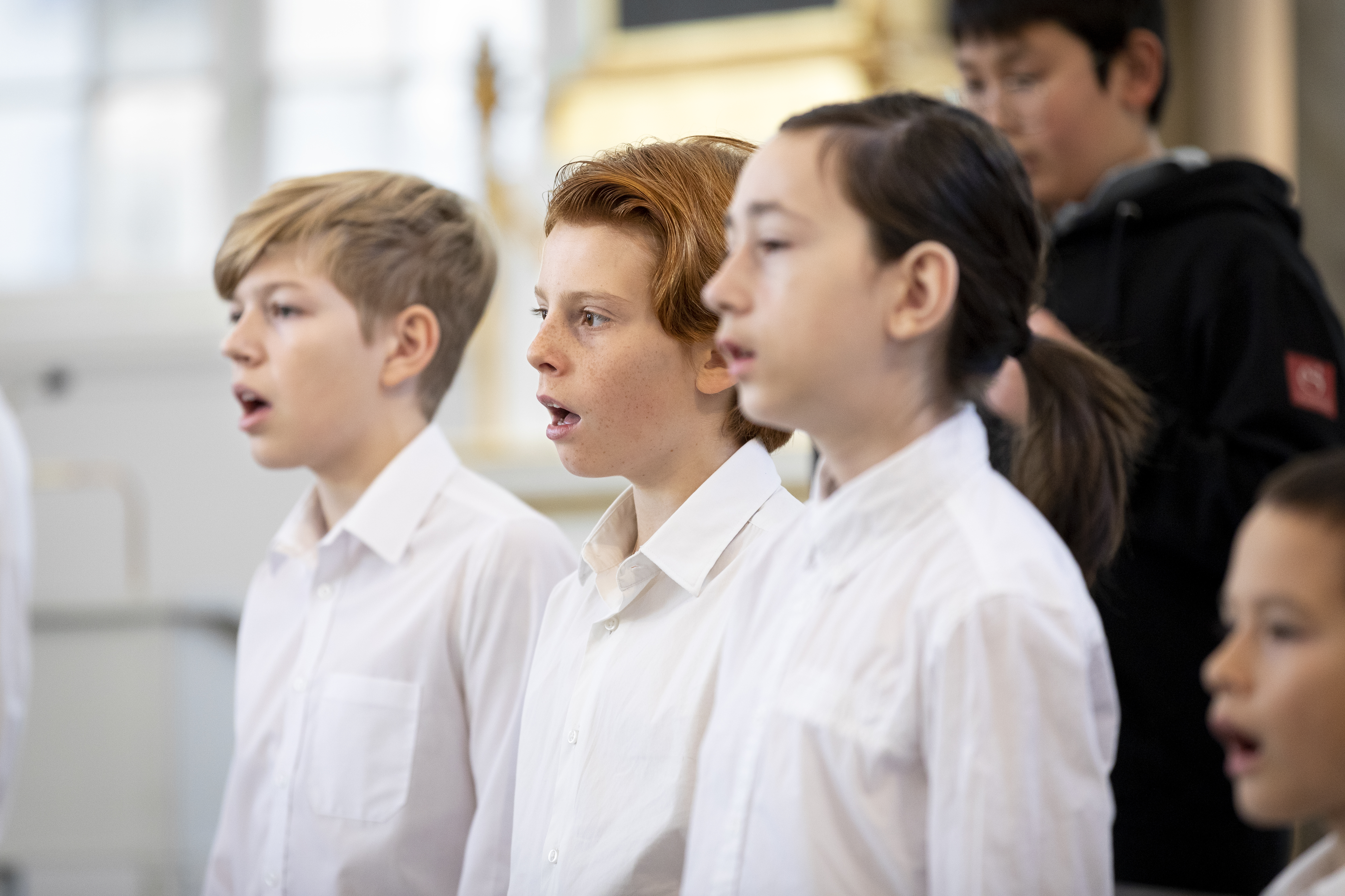 Närbild på medlemmar i en barnkör som sjunger i en kyrka.