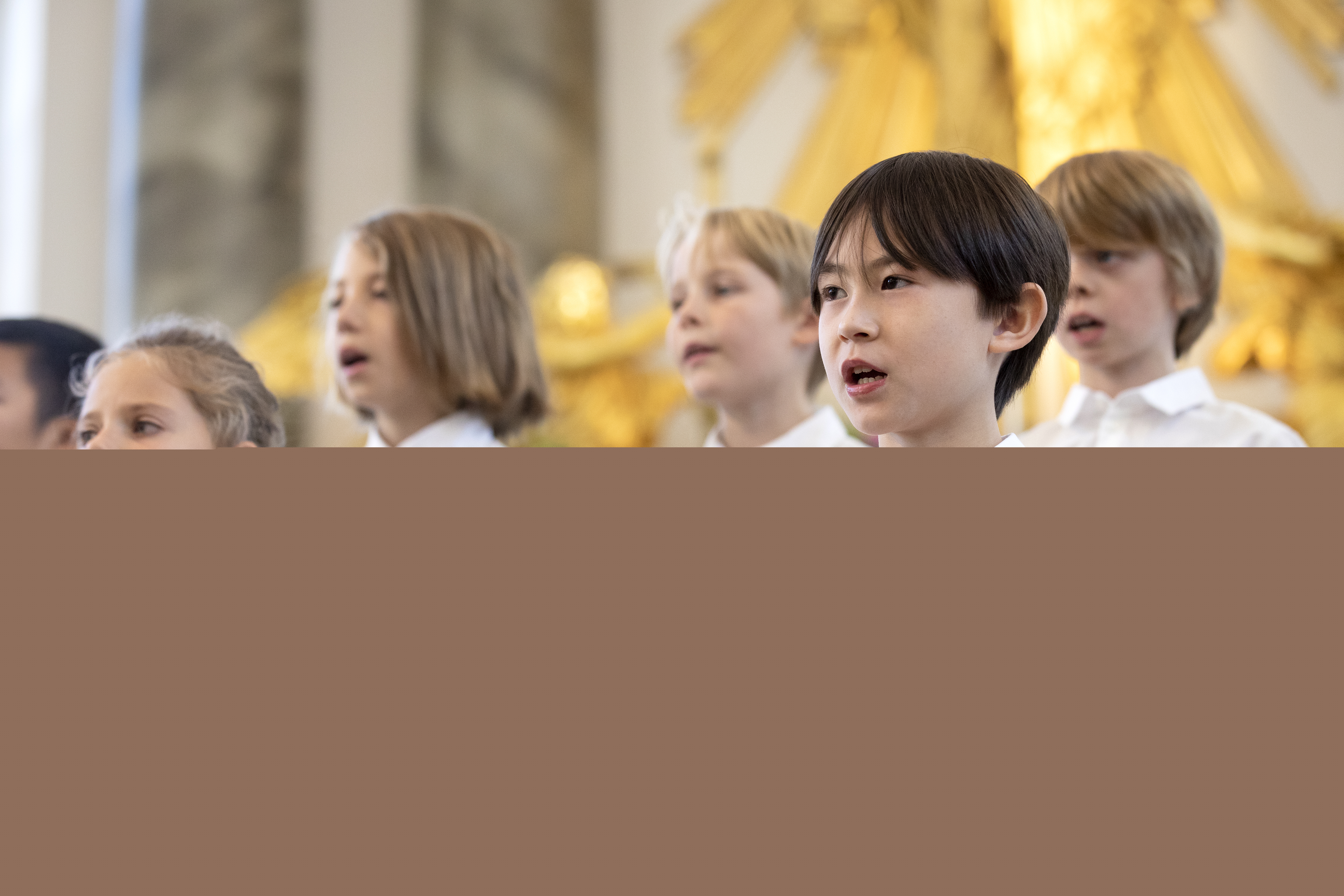 Medlemmar i en barnkör står och sjunger i en kyrka.