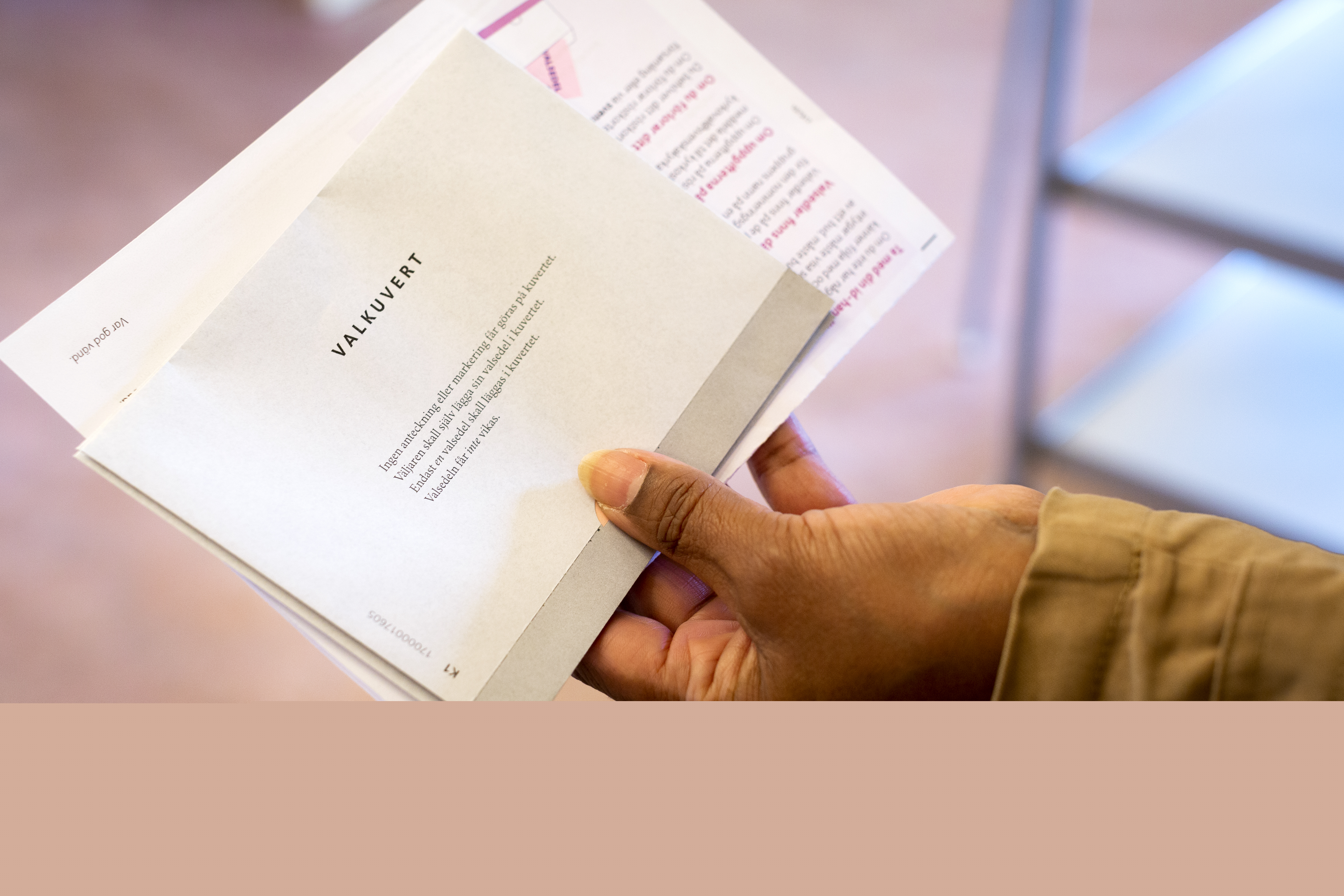 Närbild på en hand som håller ett valkuvert och ett röstkort.