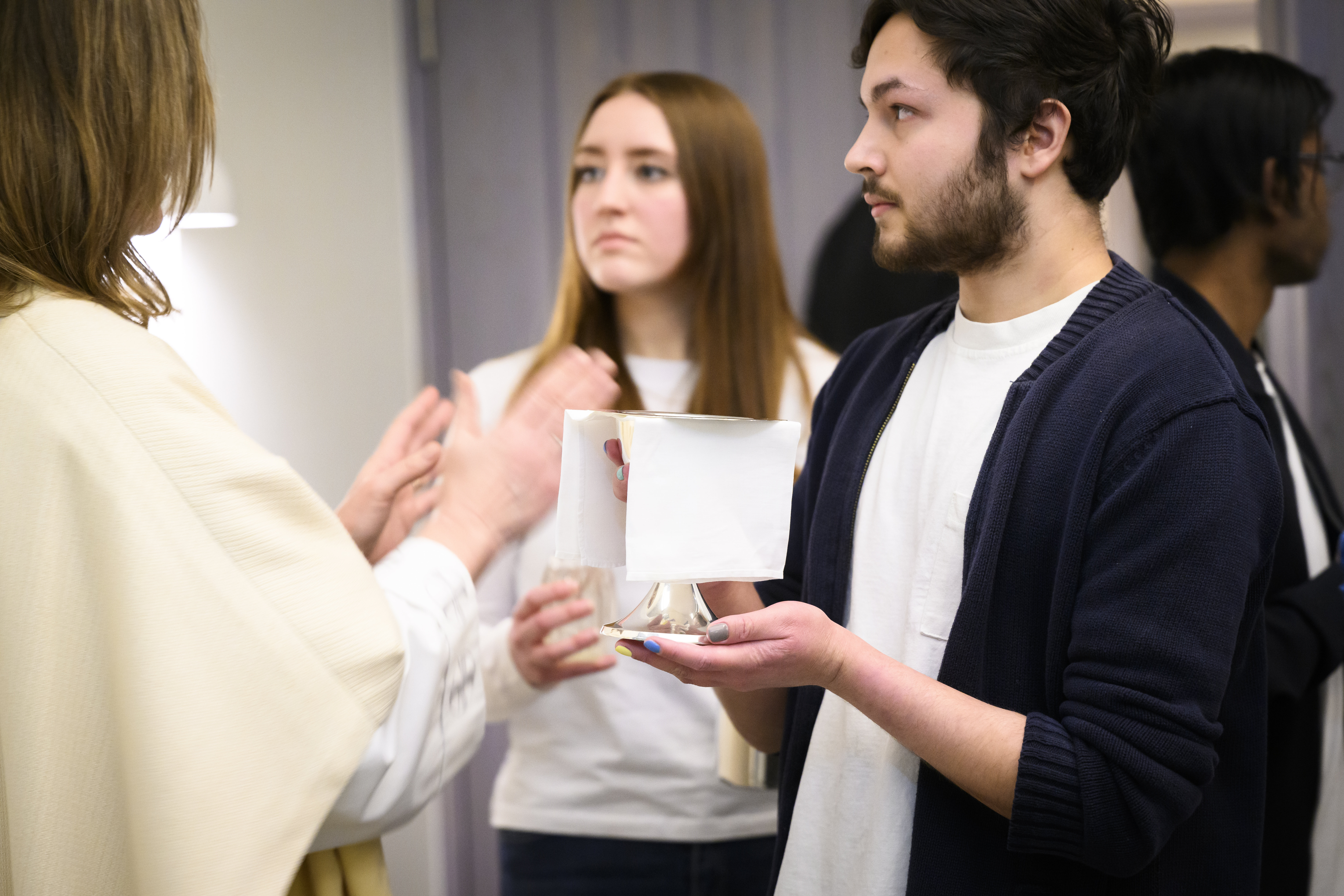 En präst och ett par ungdomar förbereder sig för att ge nattvard.