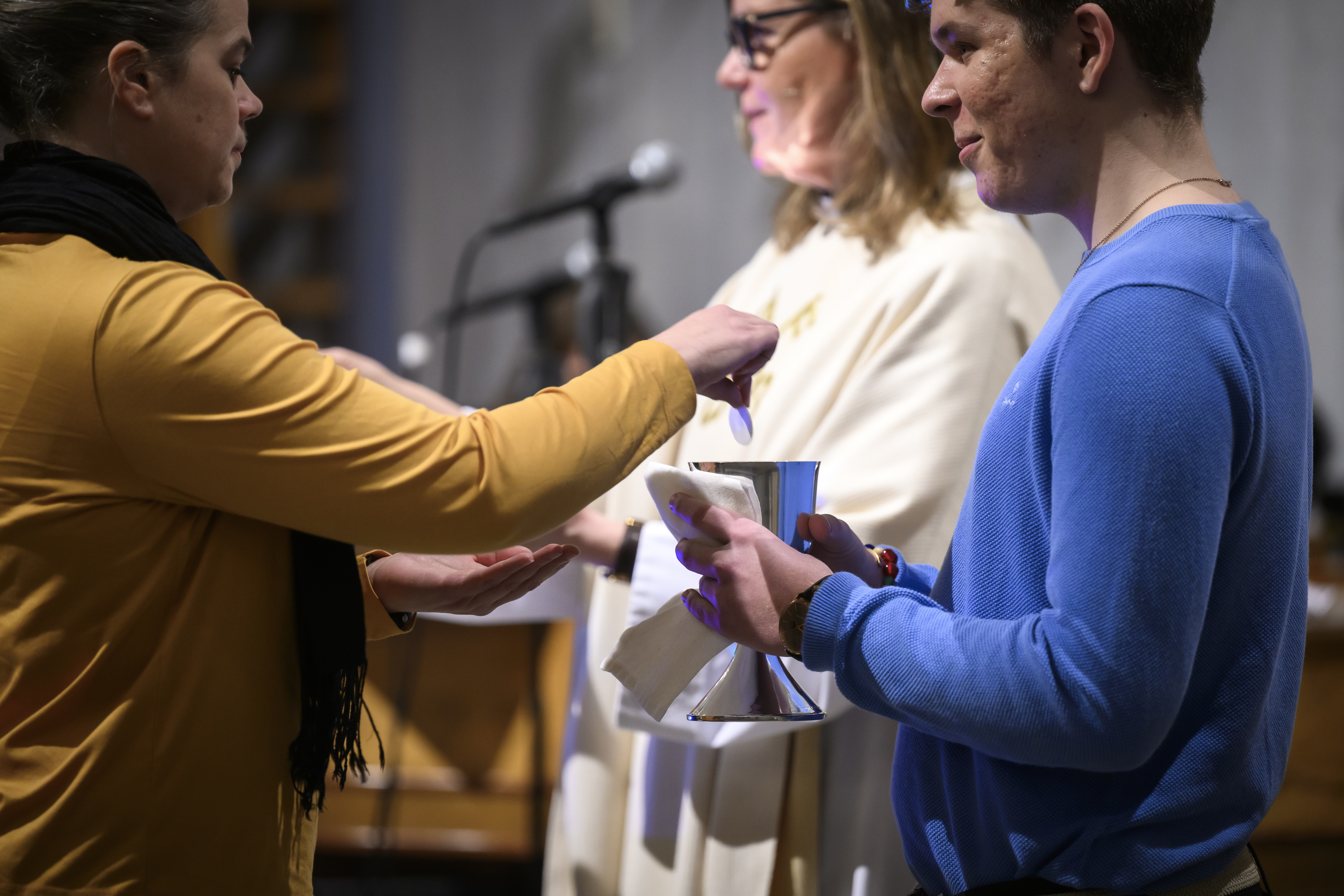 En kvinna doppar en oblat i en nattvardskalk.