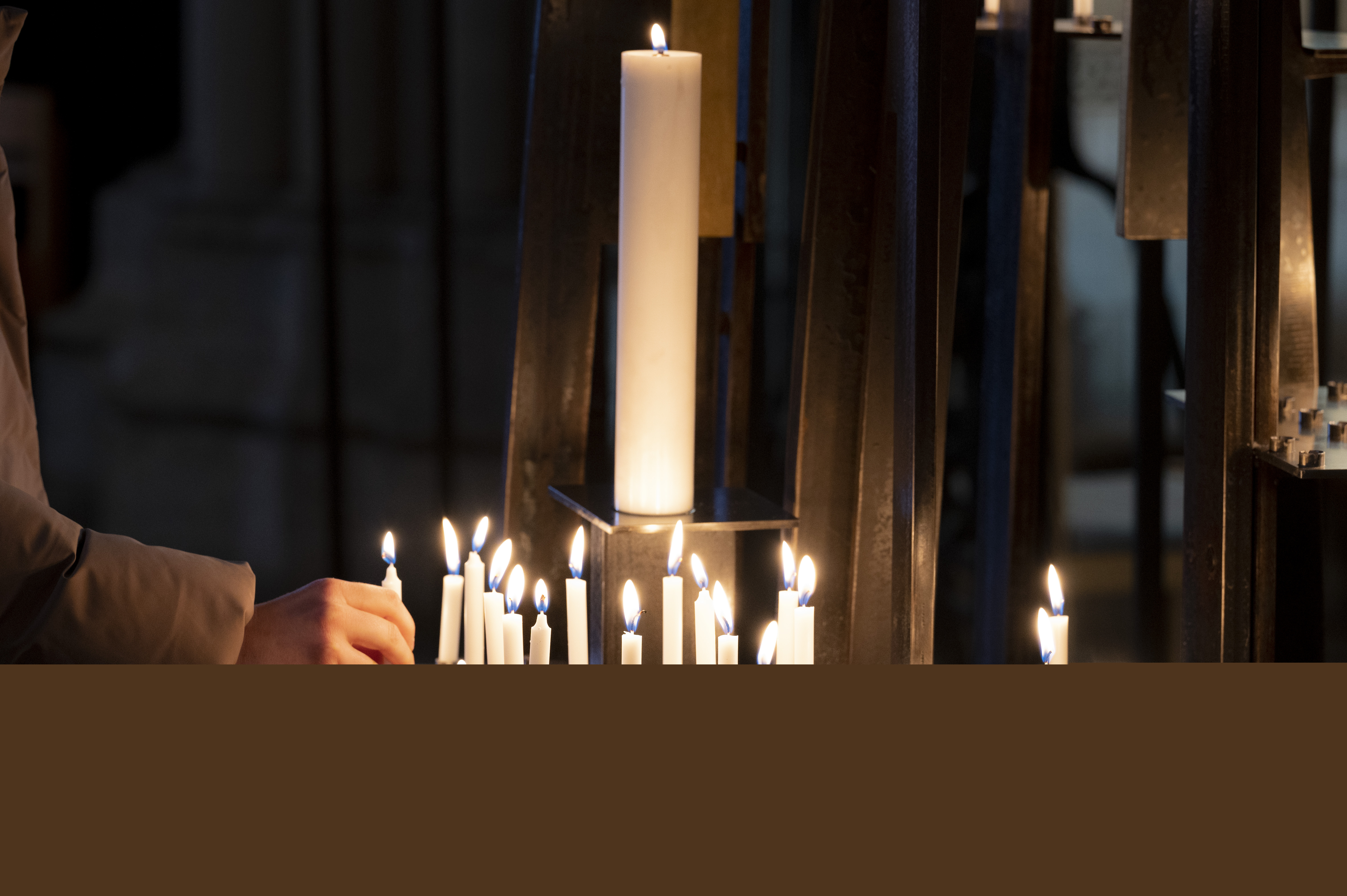 En hand sätter ett tänt ljus i en ljusbärare.