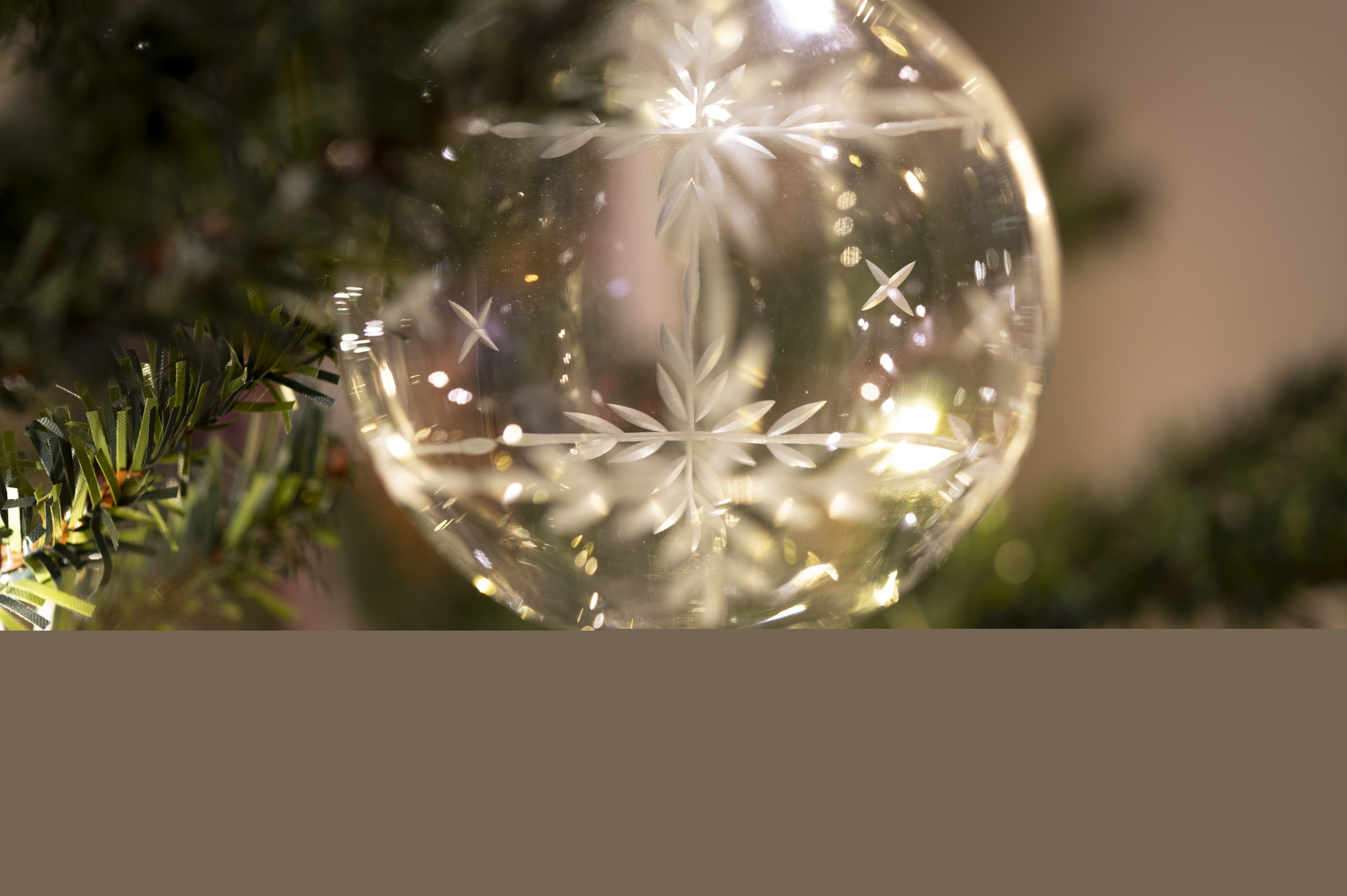 Närbild på en ljusgul genomskinlig julgranskula i en gran. B