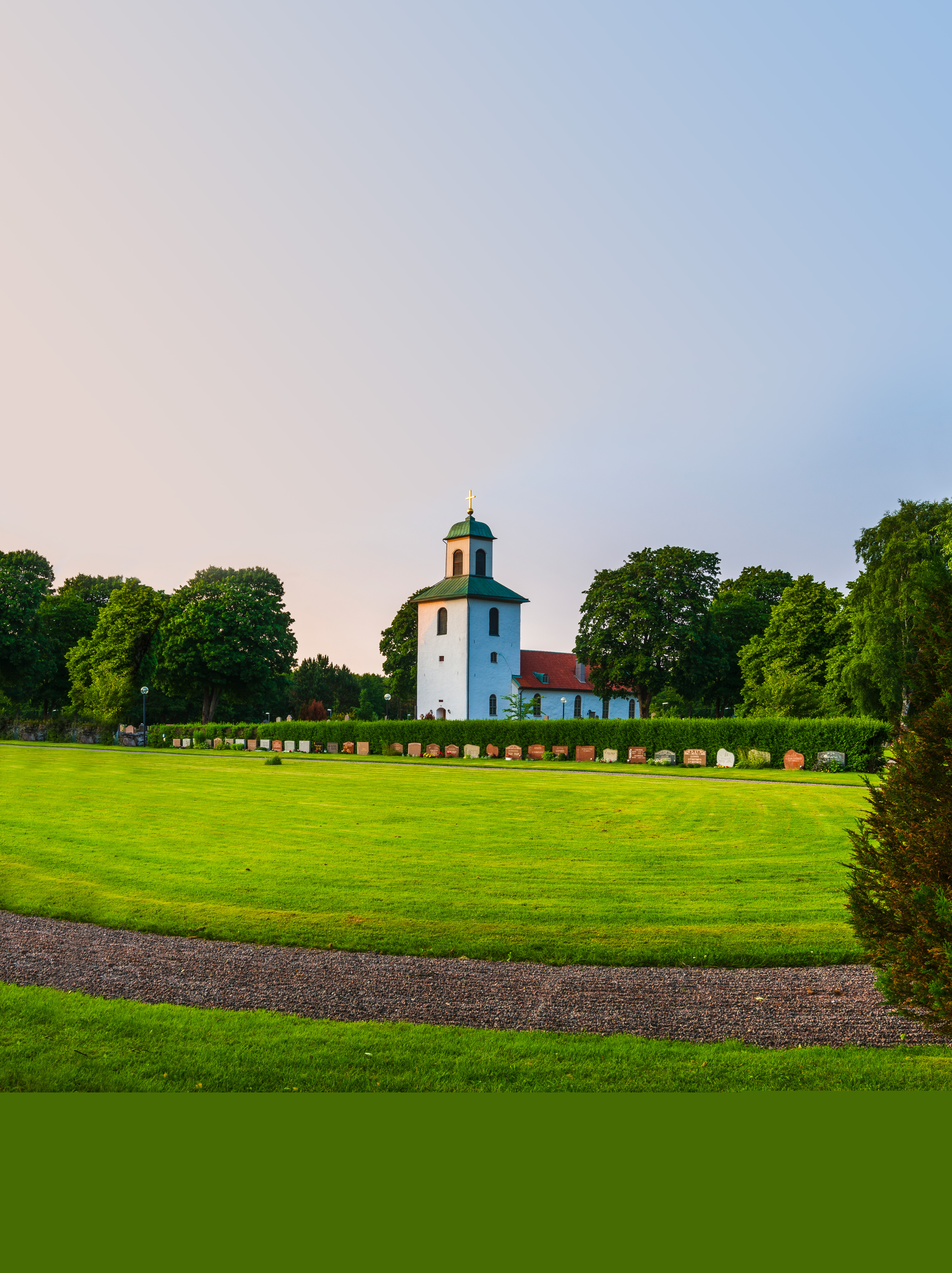 En vit landsbygdskyrka bland lummiga träd.