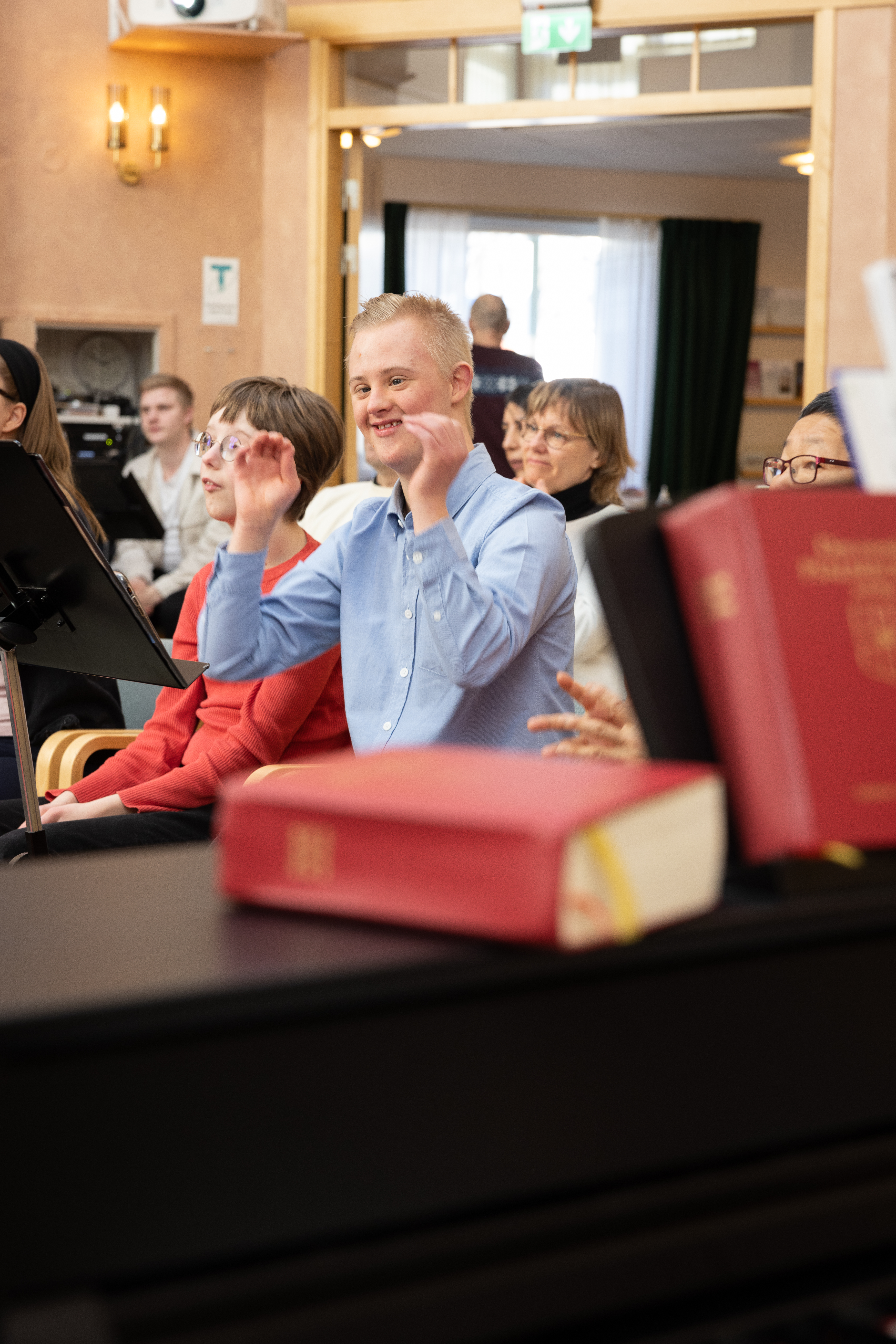En pojke med Downs syndrom sitter och gestikulerar med sina armar.