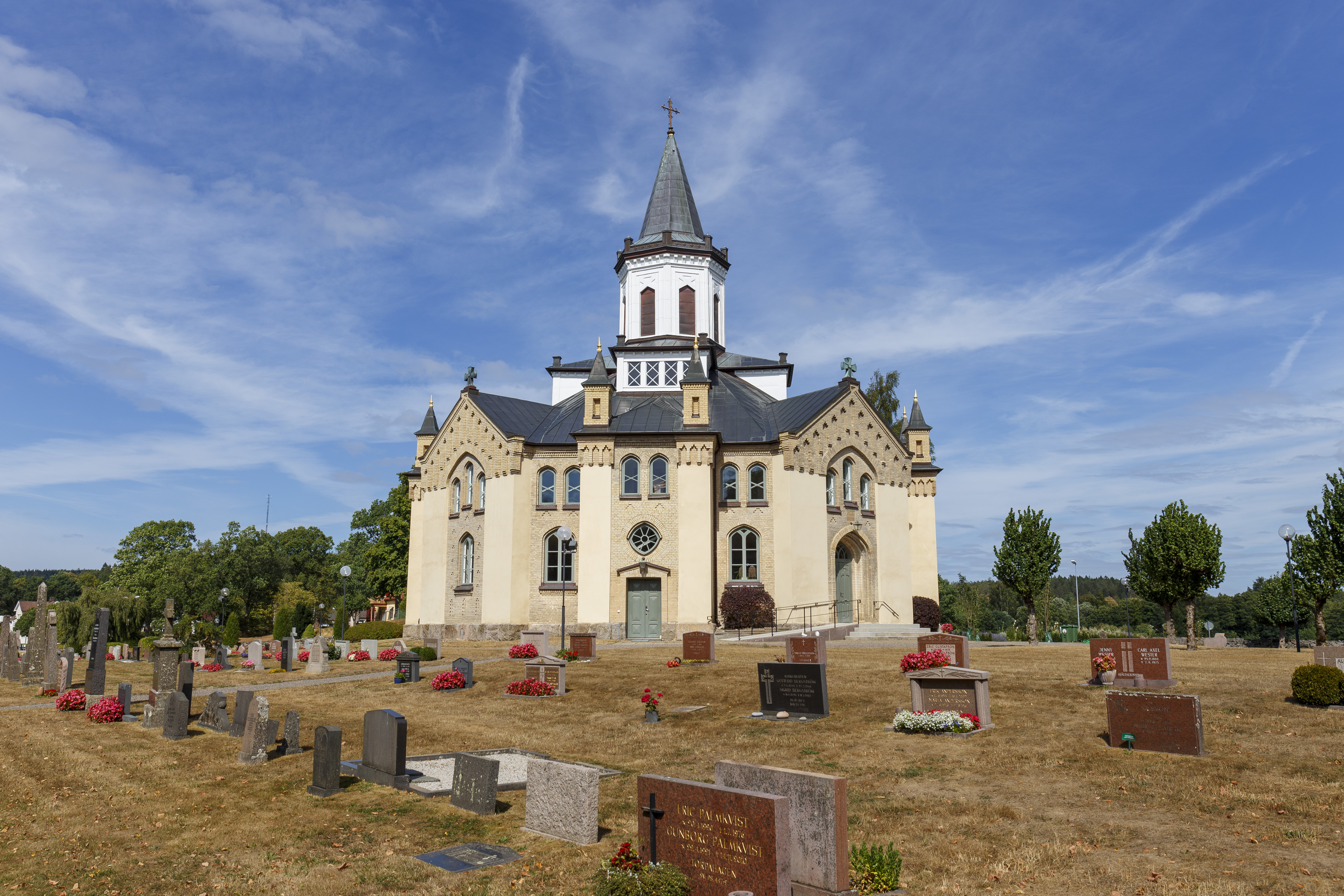 En åttkantig kyrka och en kyrkogård i solen.