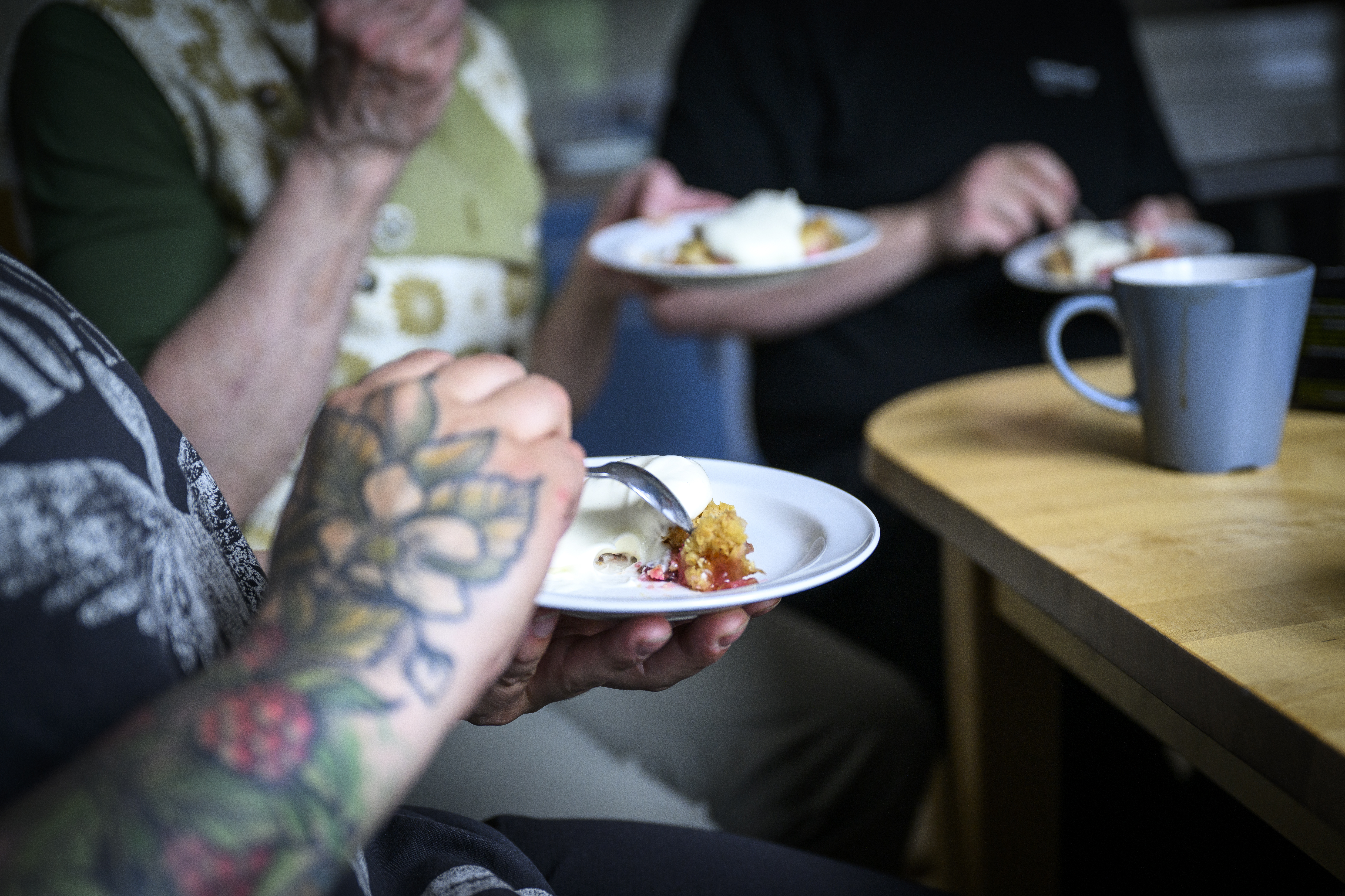 Några personer sitter runt ett bord och fikar.