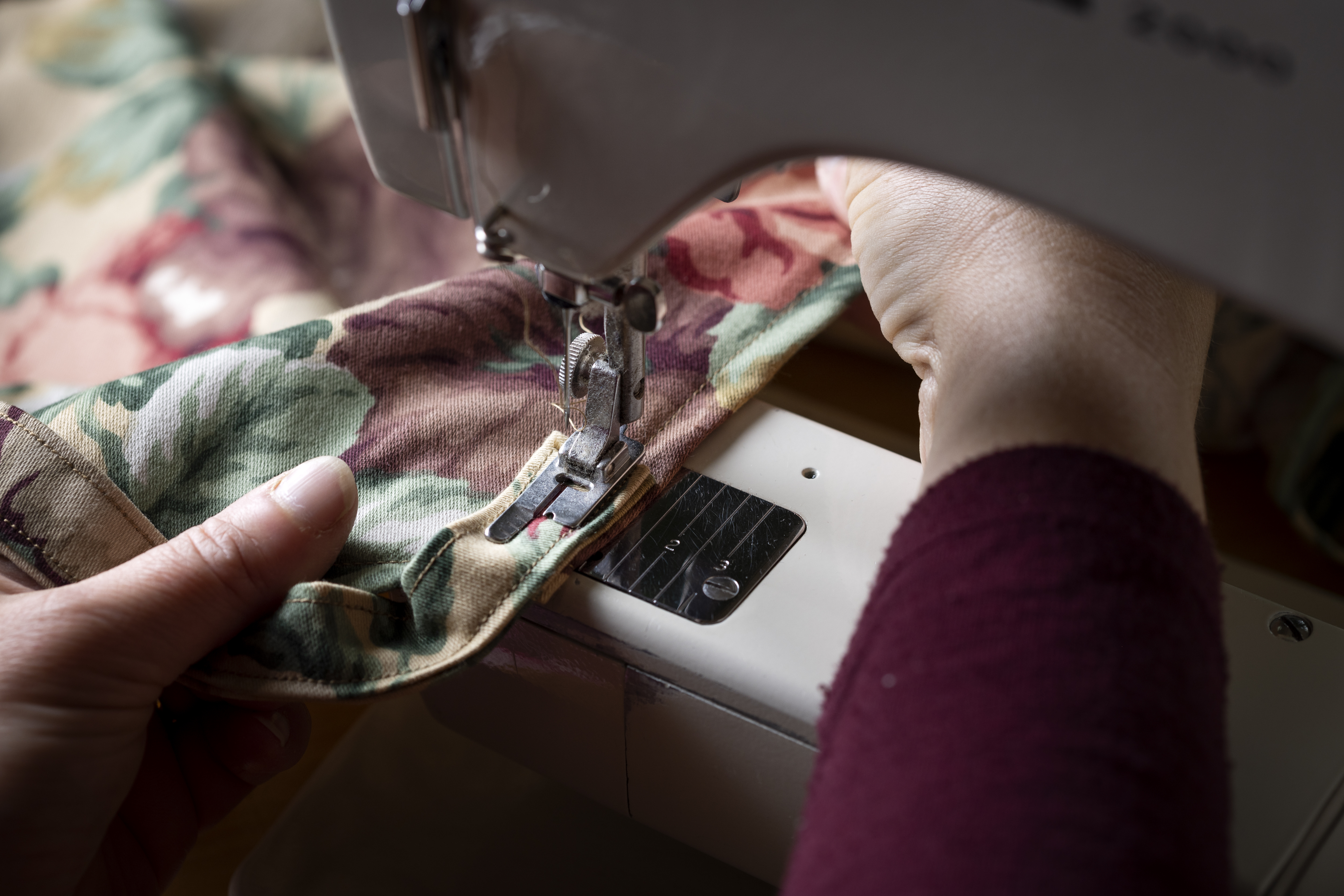 Närbild på någon som syr på en symaskin.
