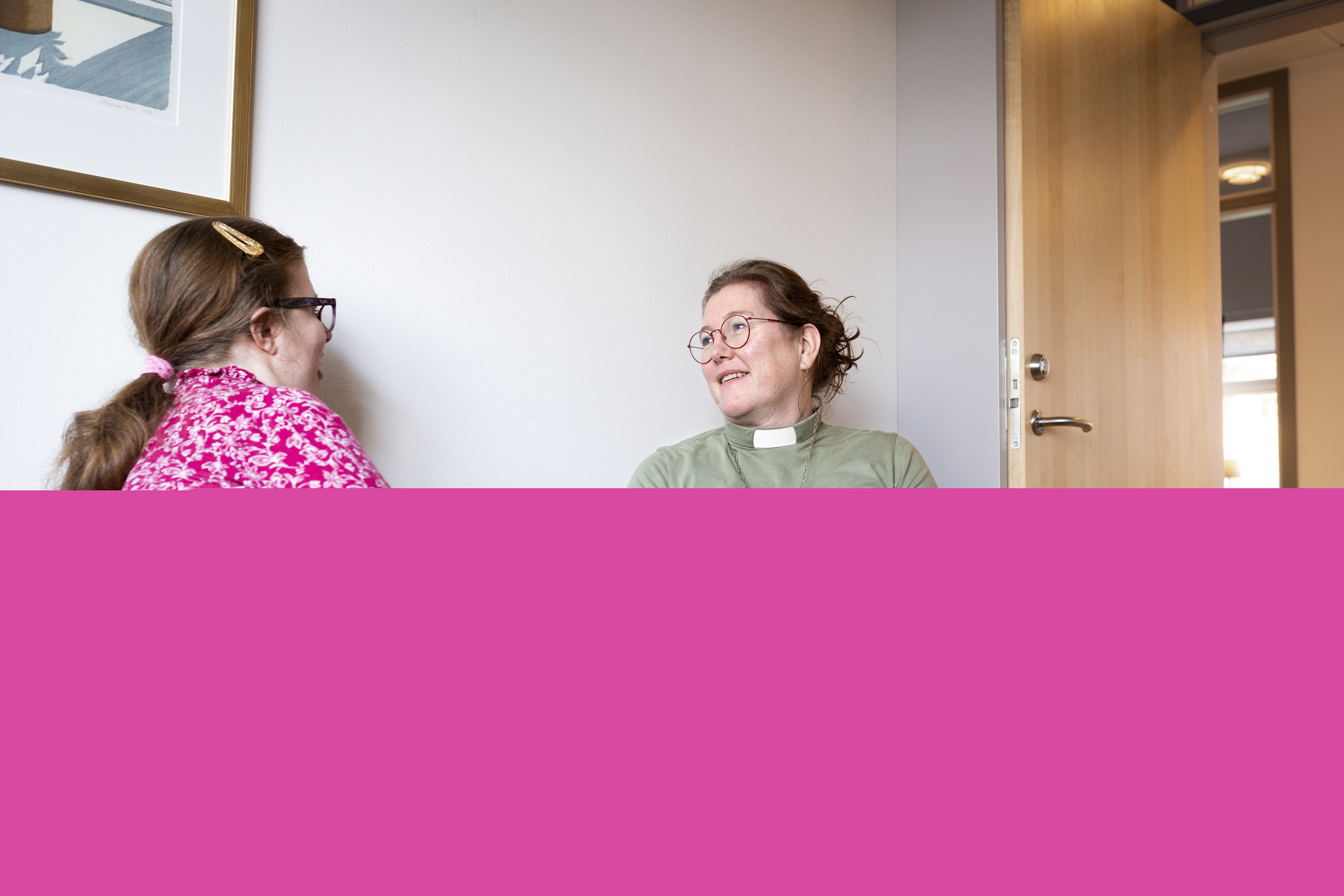 En kvinnlig diakon sitter och samtalar med en ung tjej i en soffa.