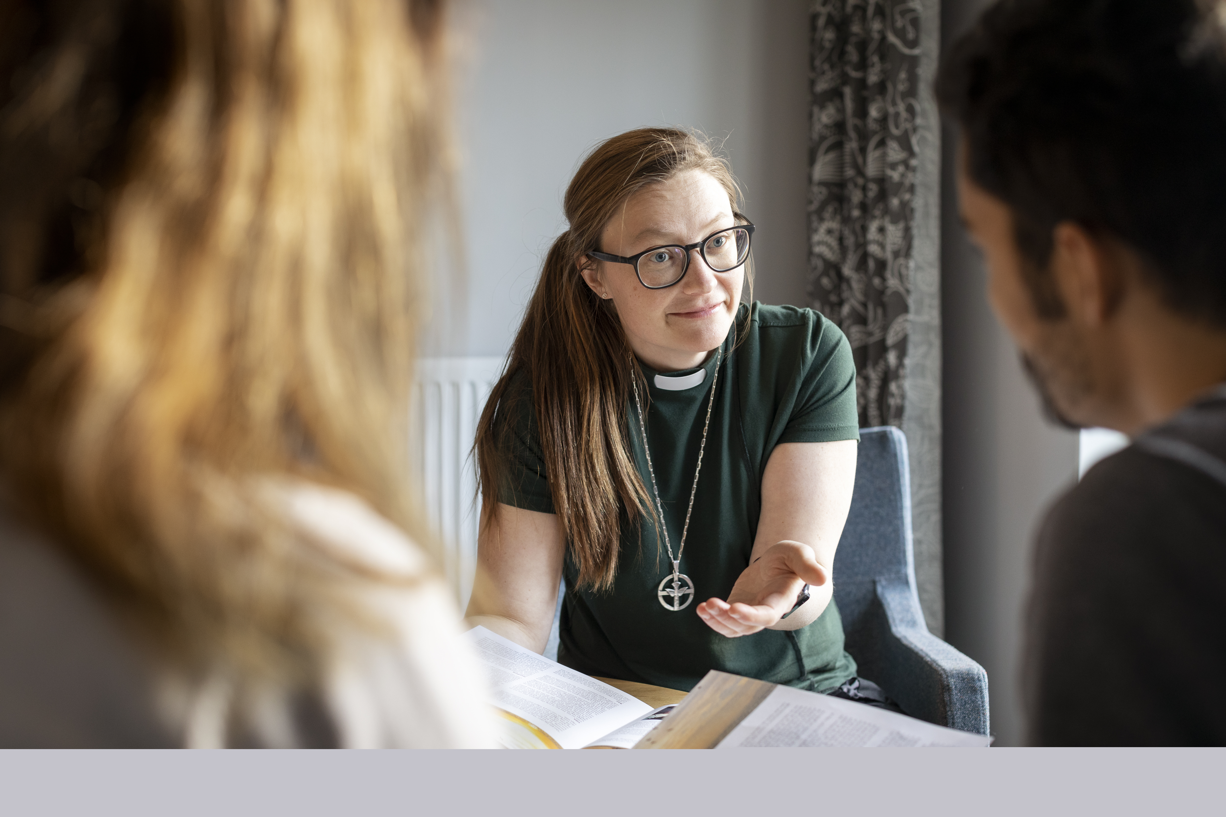 En kvinnlig diakon sitter och samtalar med en man och en kvinna.