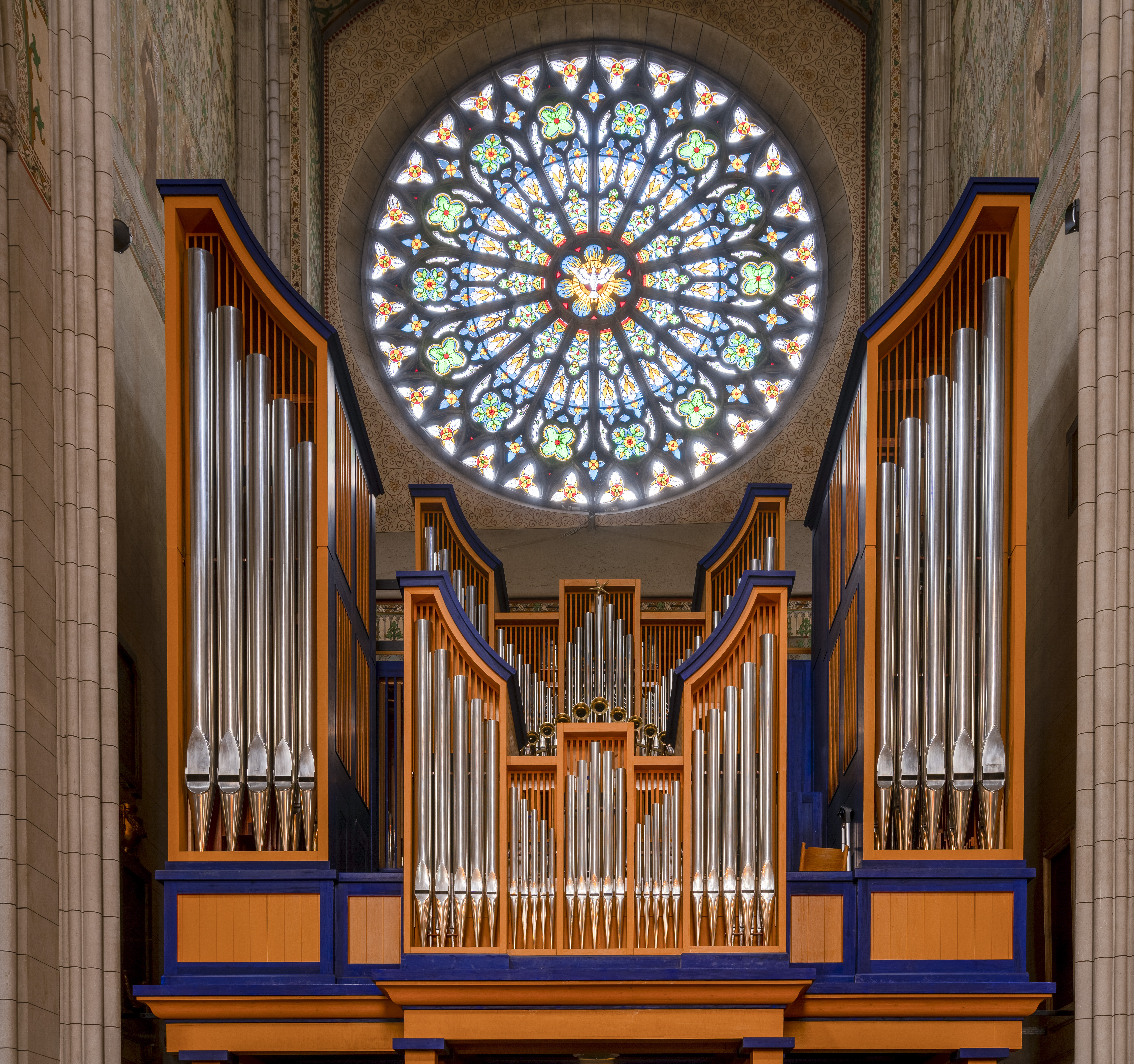 En runt och färgglatt kyrkfönster ovanför en kyrkorgel.