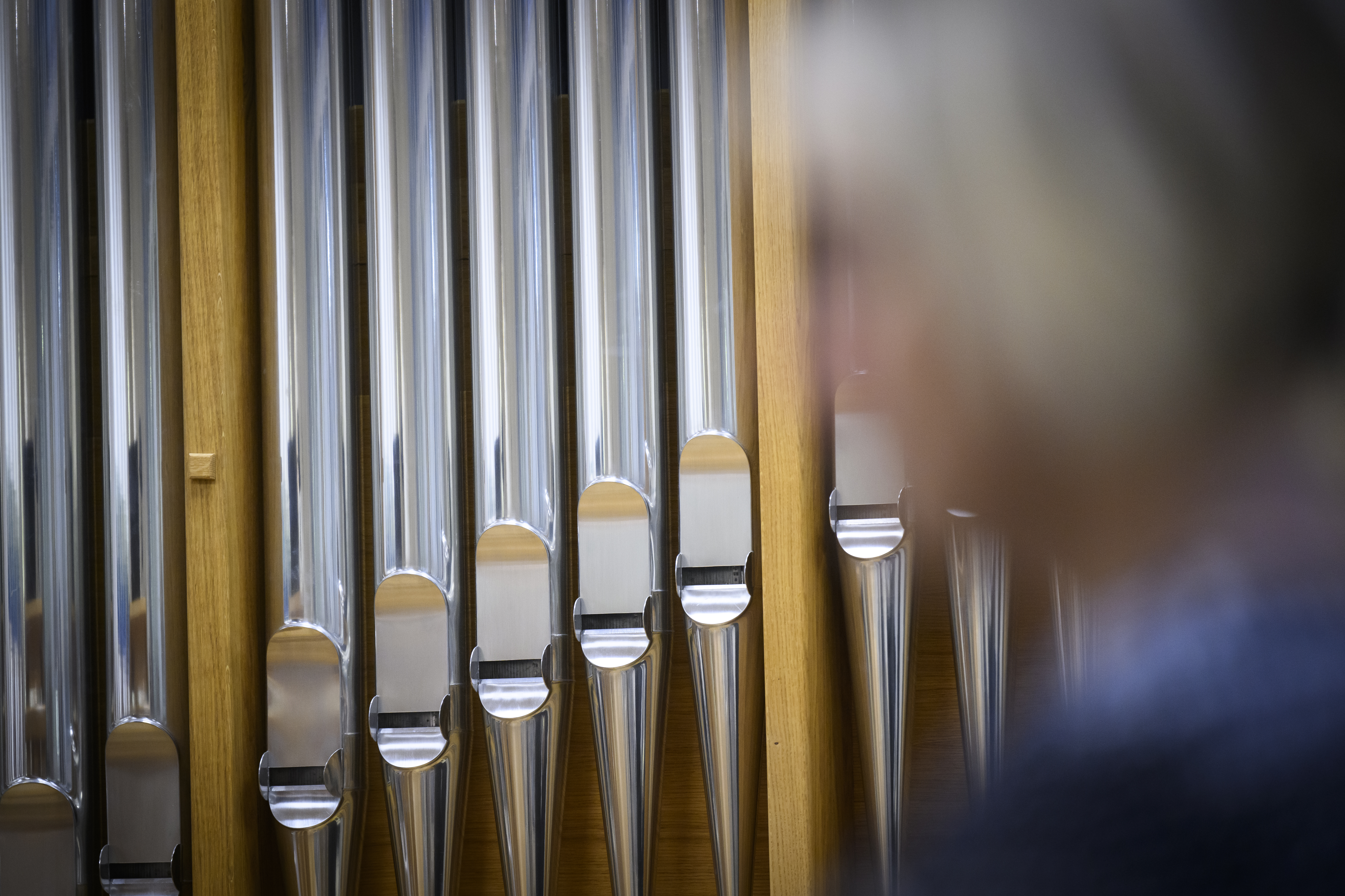 Metallfärgade orgelpipor. En person syns suddigt i förgrunden.