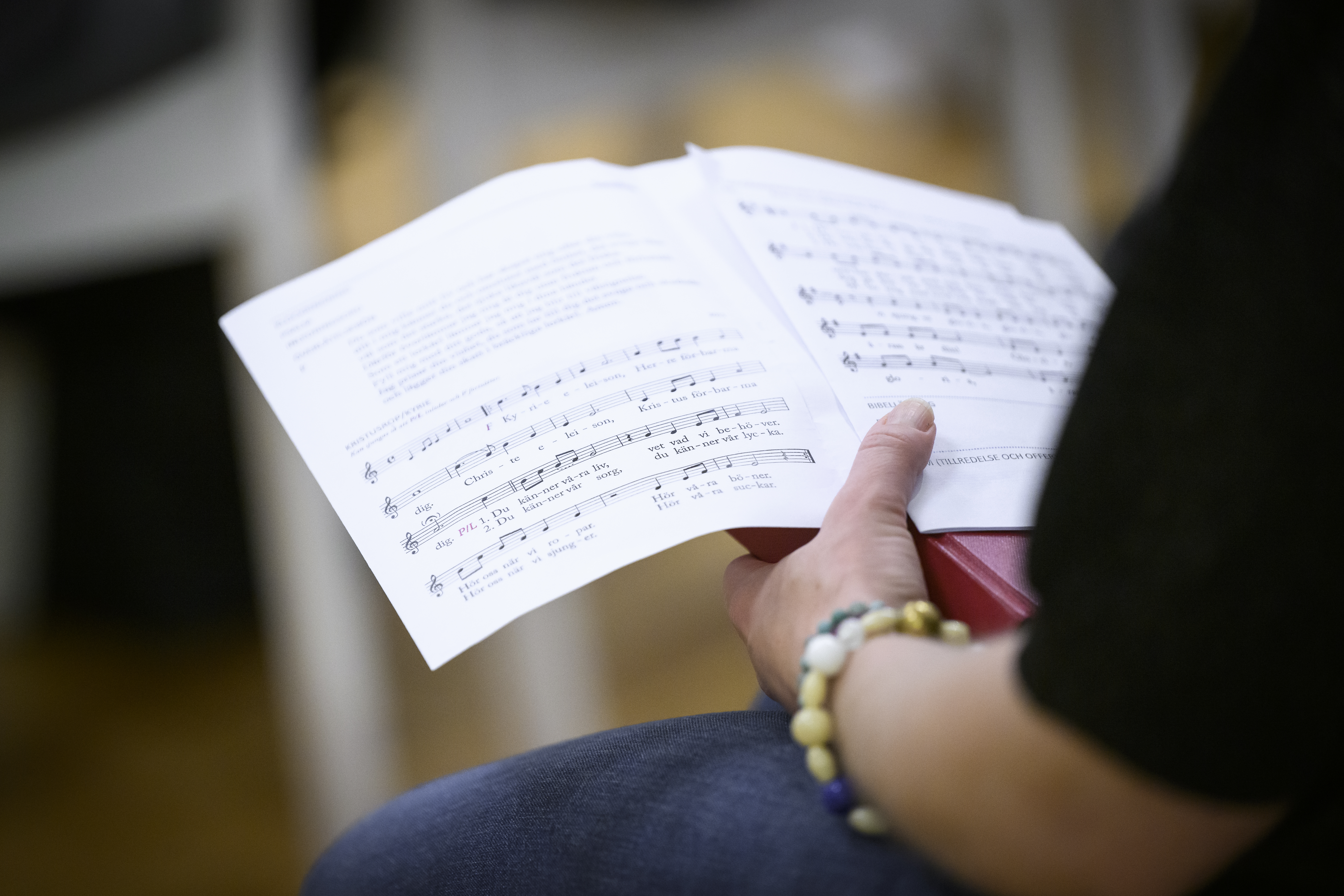 En person sitter och läser i ett sånghäfte.