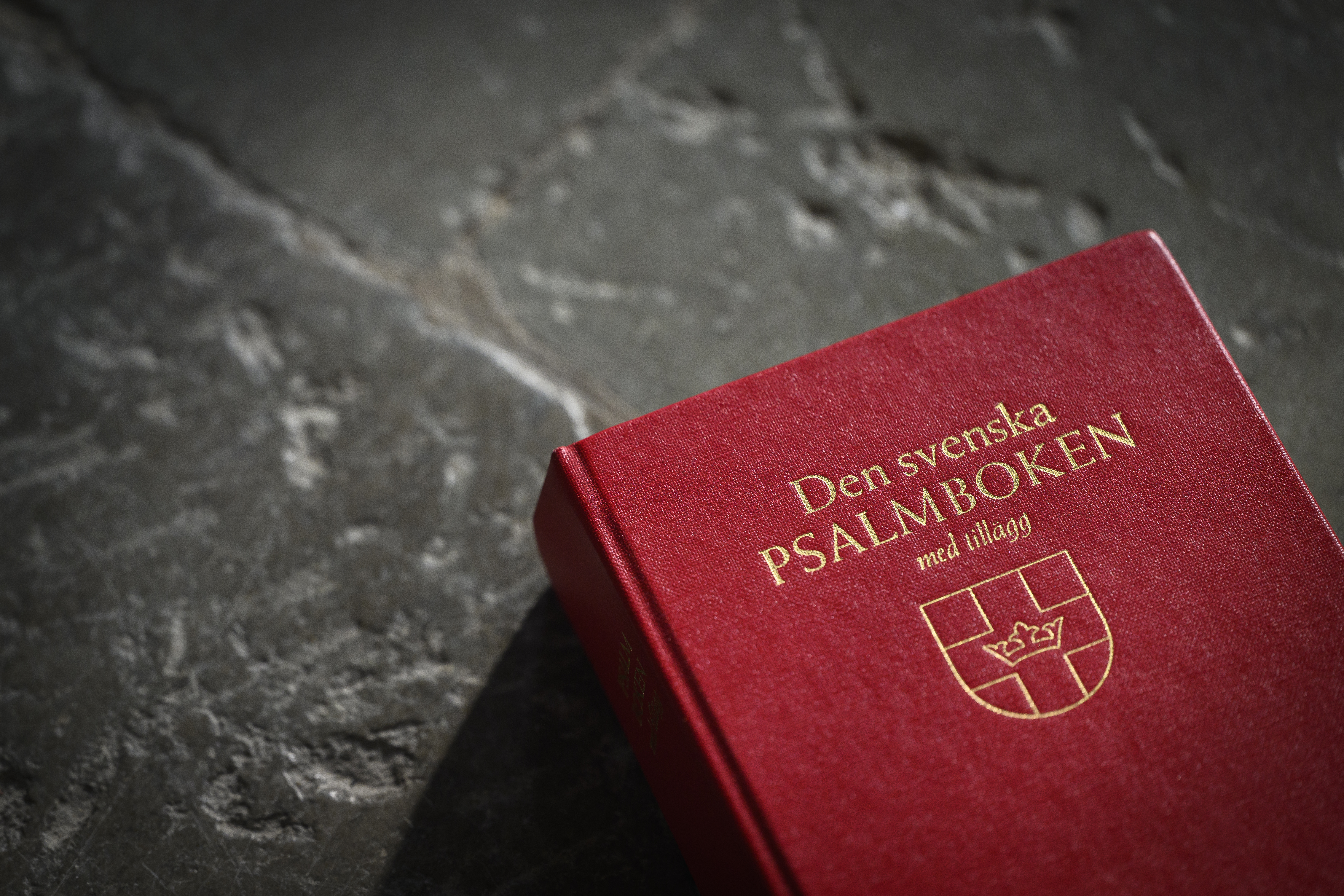 Närbild på en psalmbok som ligger på ett stengolv.
