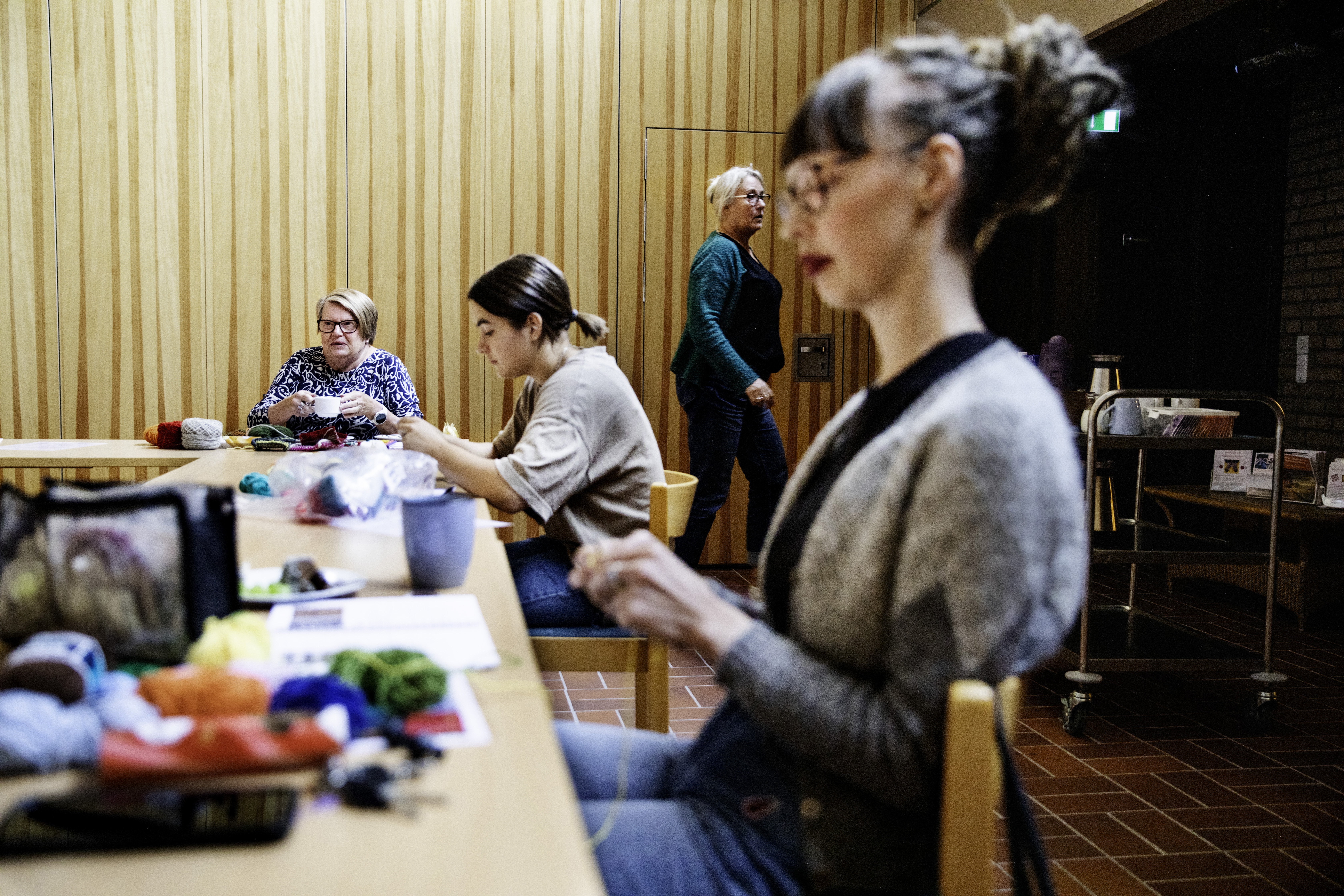 Några kvinnor sitter vid ett bord och stickar.