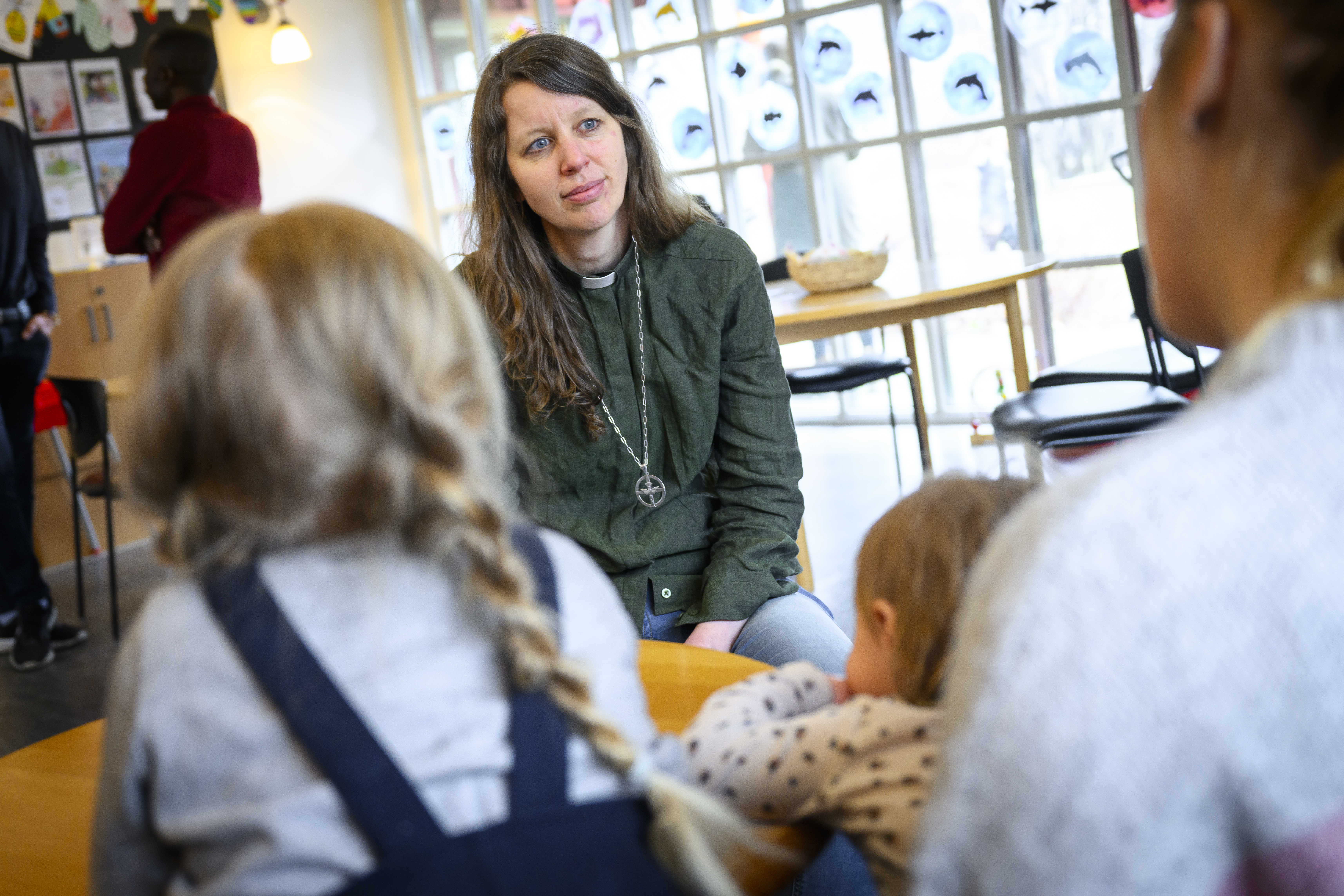 En diakon sitter och samtalar med en kvinna och två småbarn.