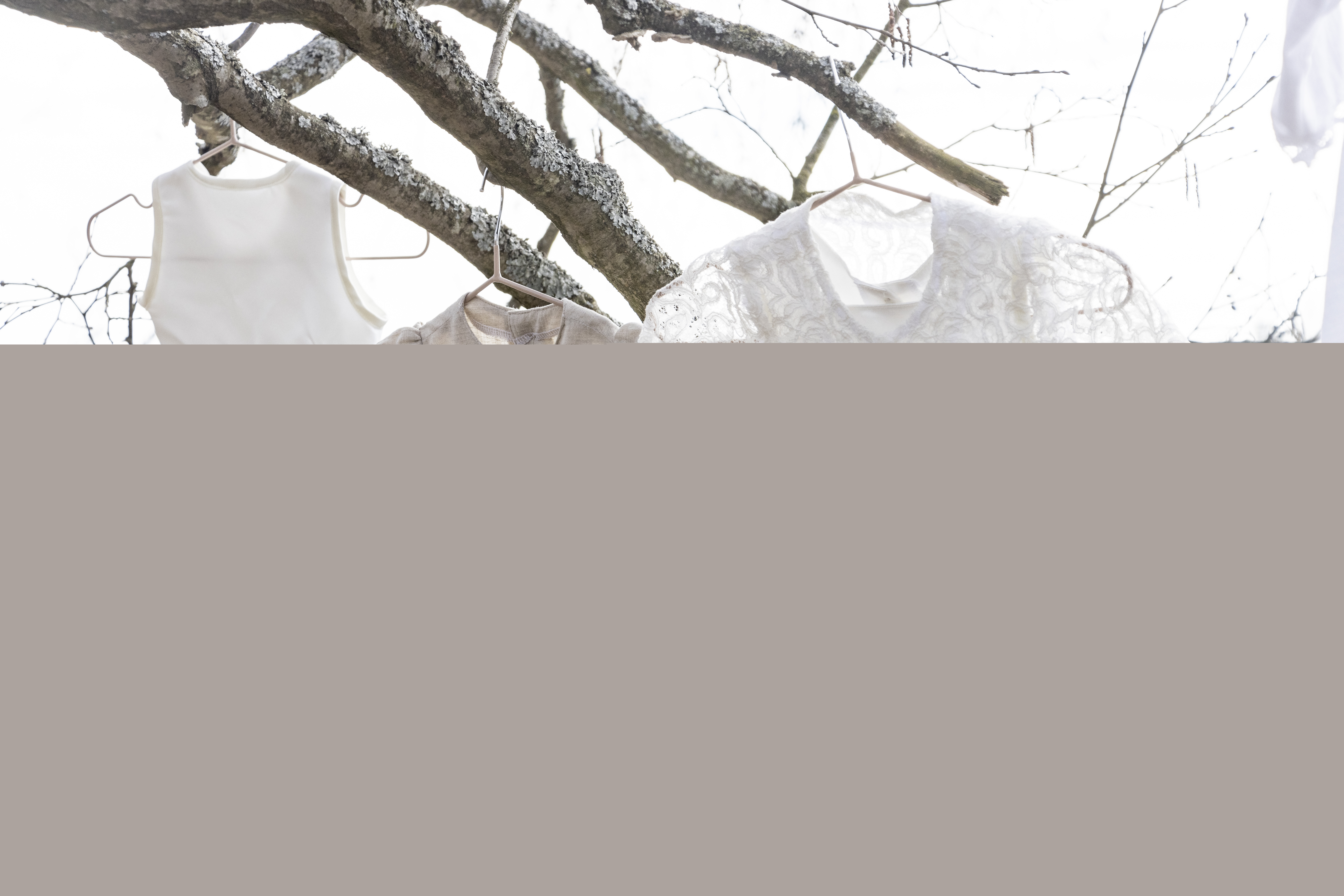 Tre olika dopklänningar hänger i ett träds grenar.