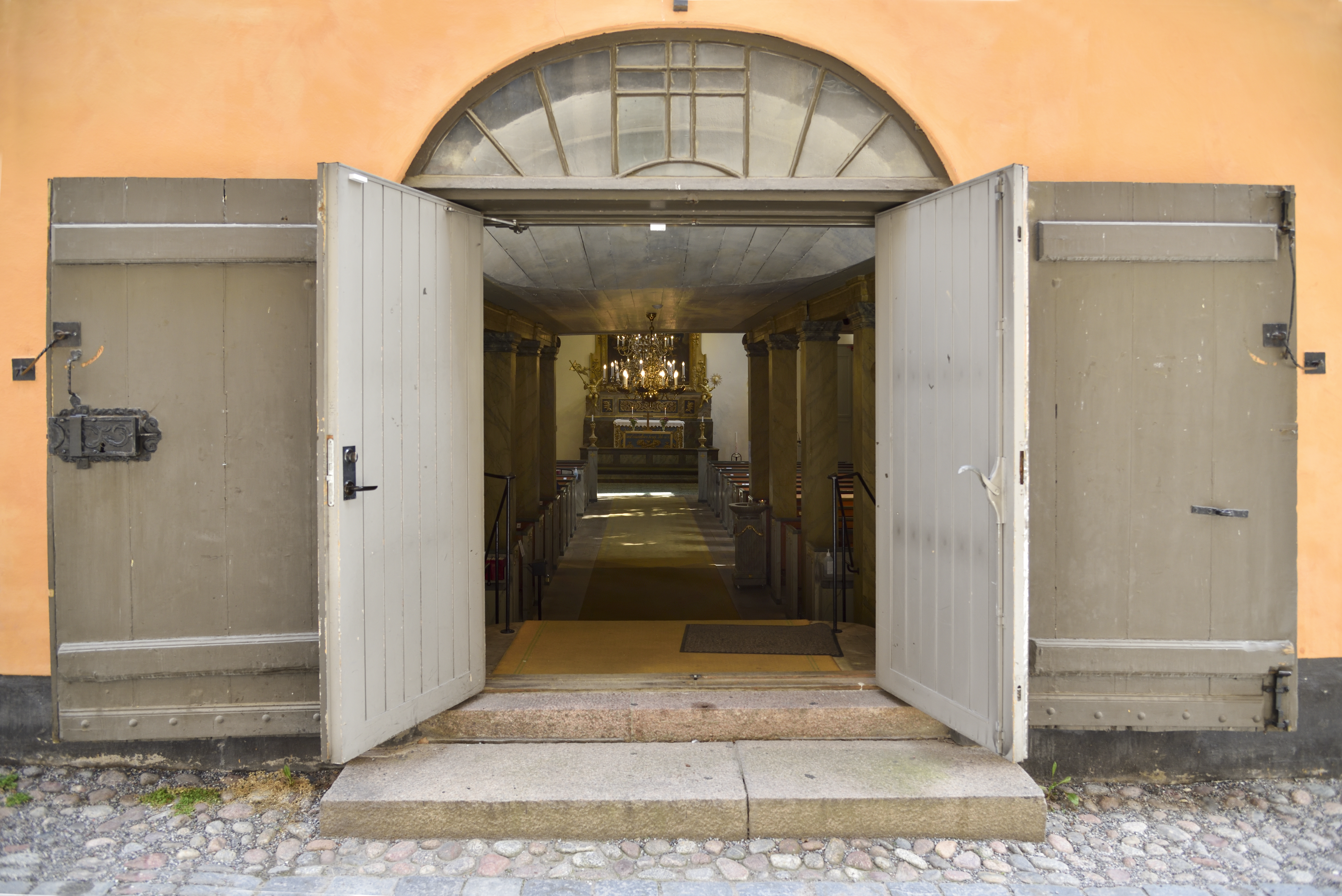 En kyrkport står öppen till en tom kyrka.
