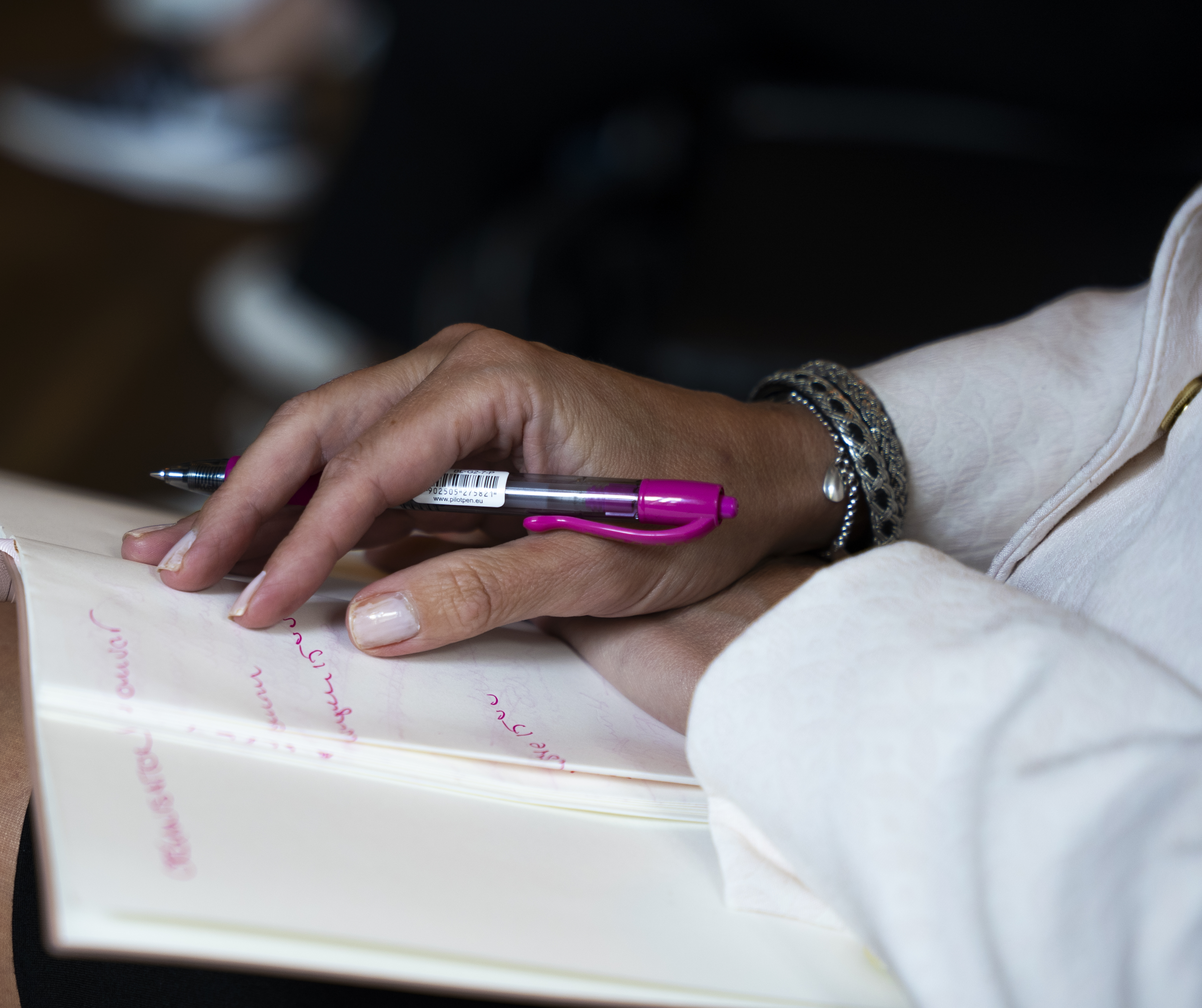 Närbild på någon som antecknar med en rosa tuschpenna.