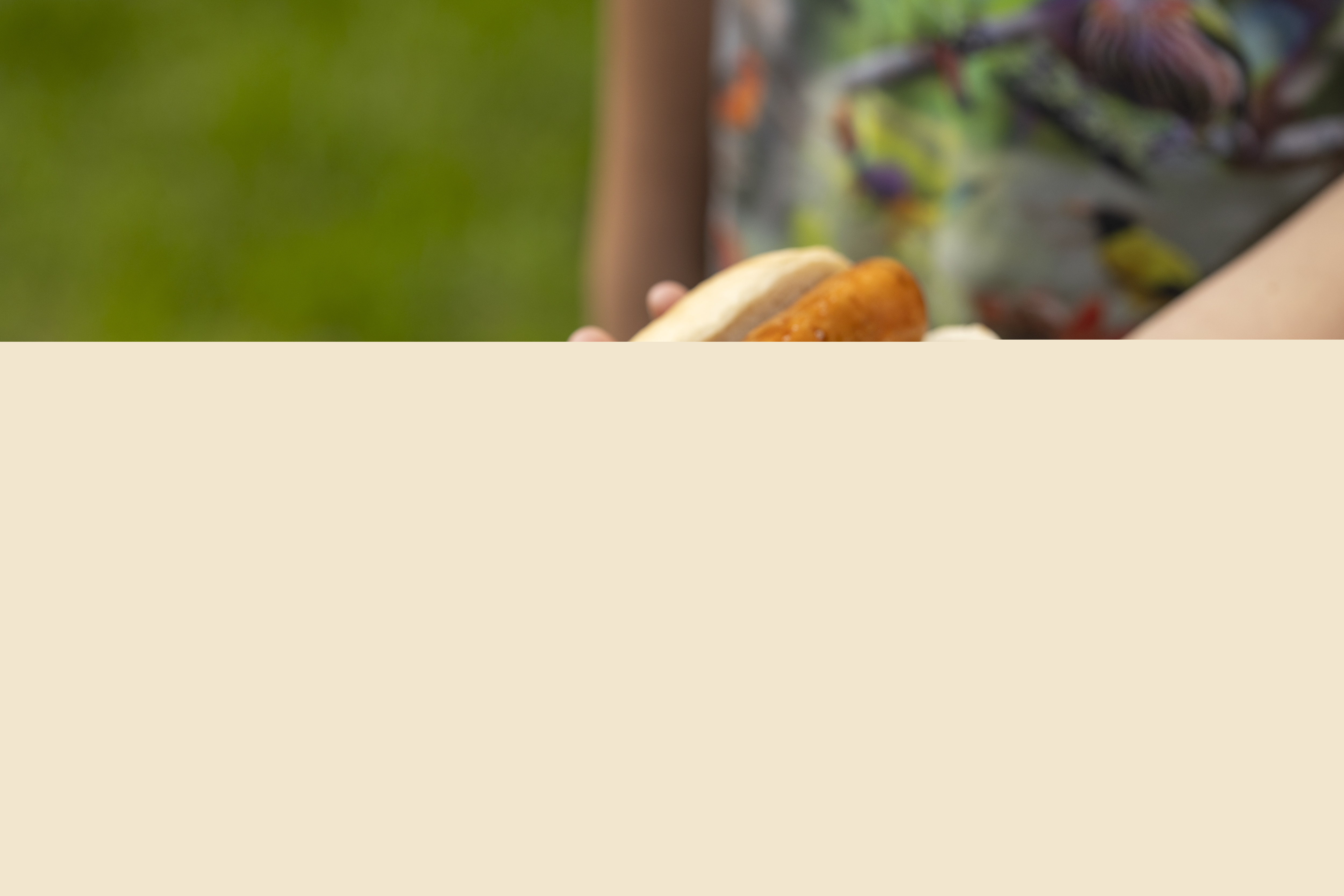 Någon lägger med tång en grillad korv till en person som håller fram ett korvbröd.