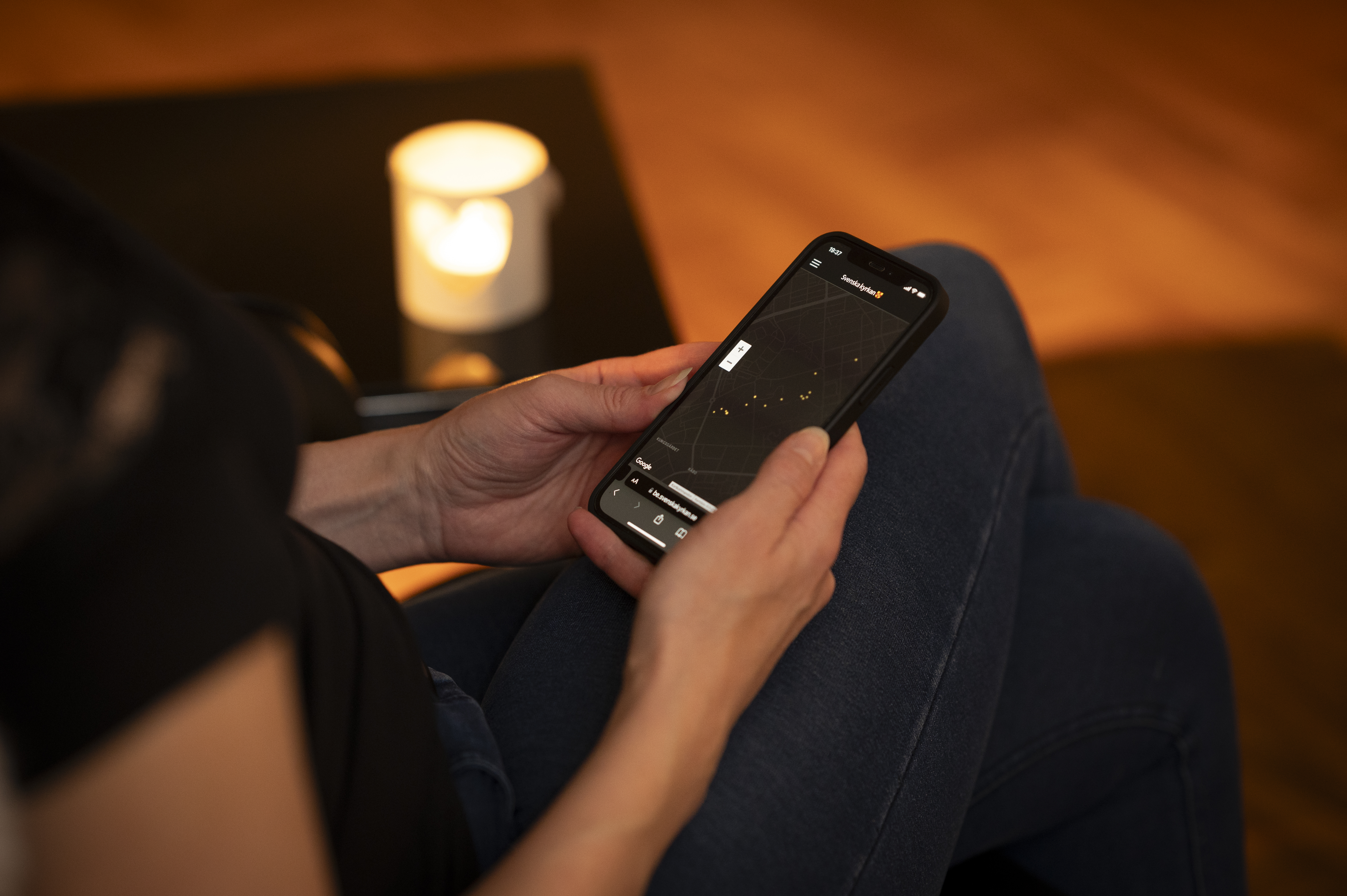 En person sitter och tittar på Svenska kyrkans bönewebb på sin smartphone.