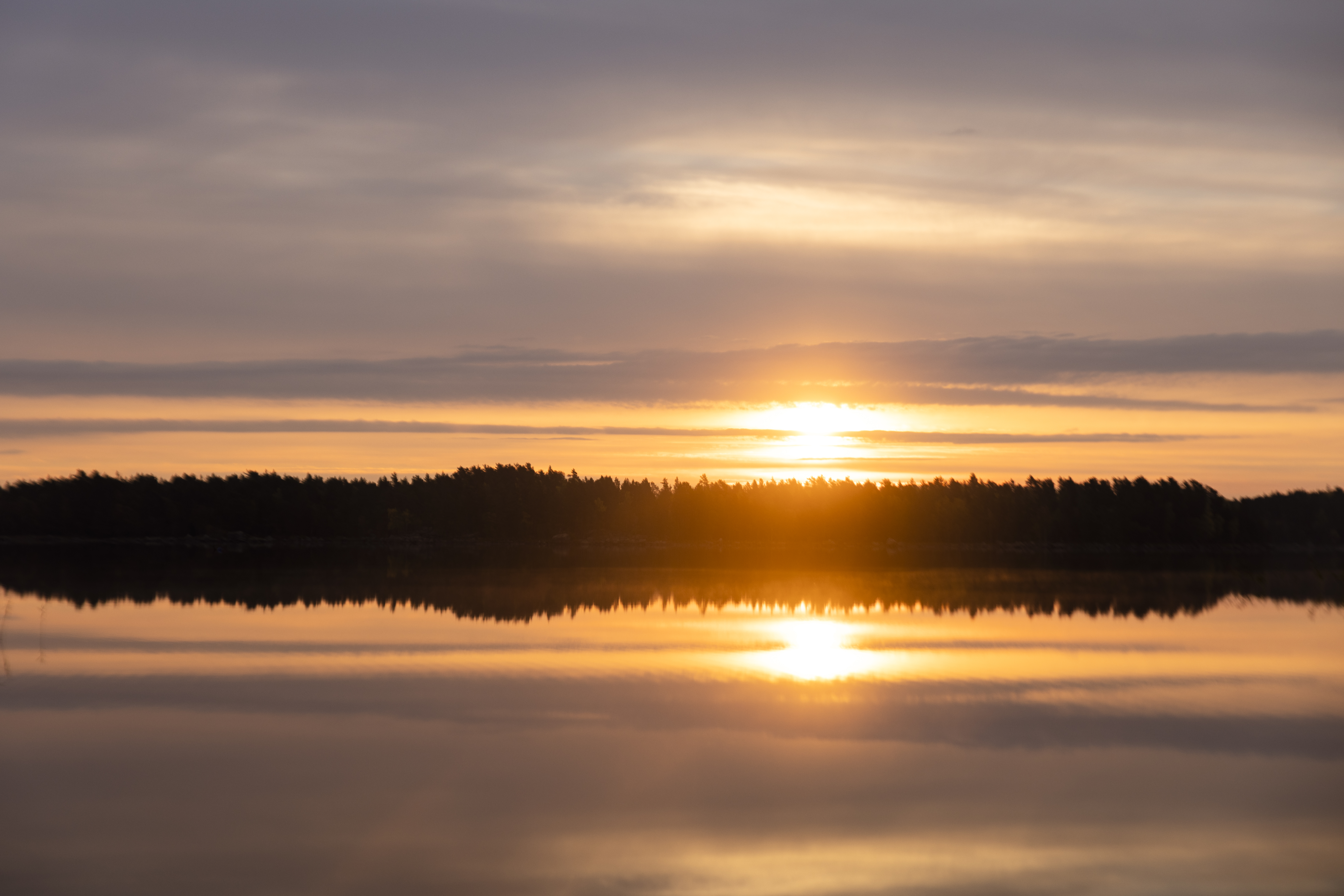 En solnedgång speglas i sjöns vattenyta.