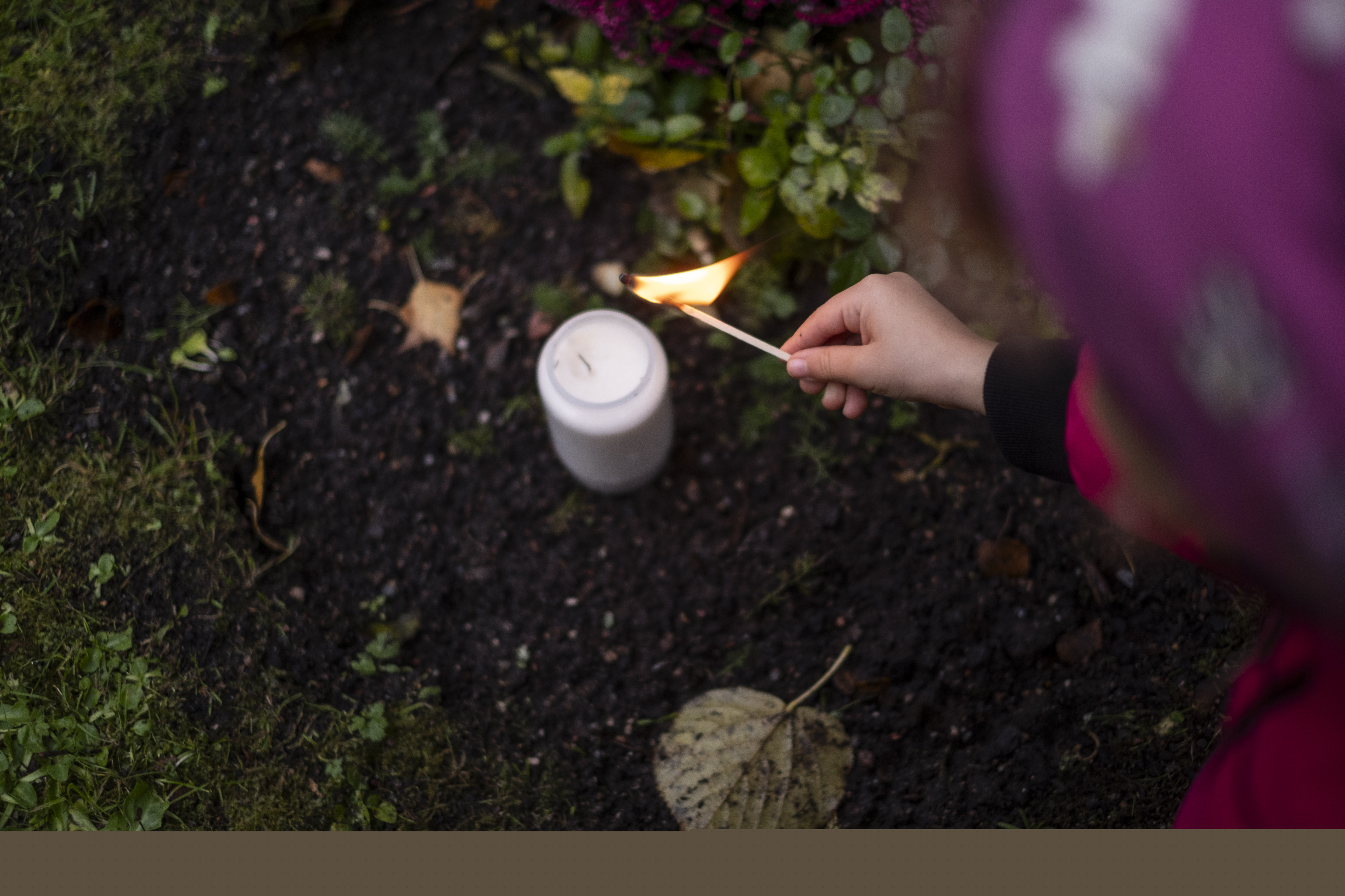 Ett litet barn tänder ett ljus vid en gravplats.