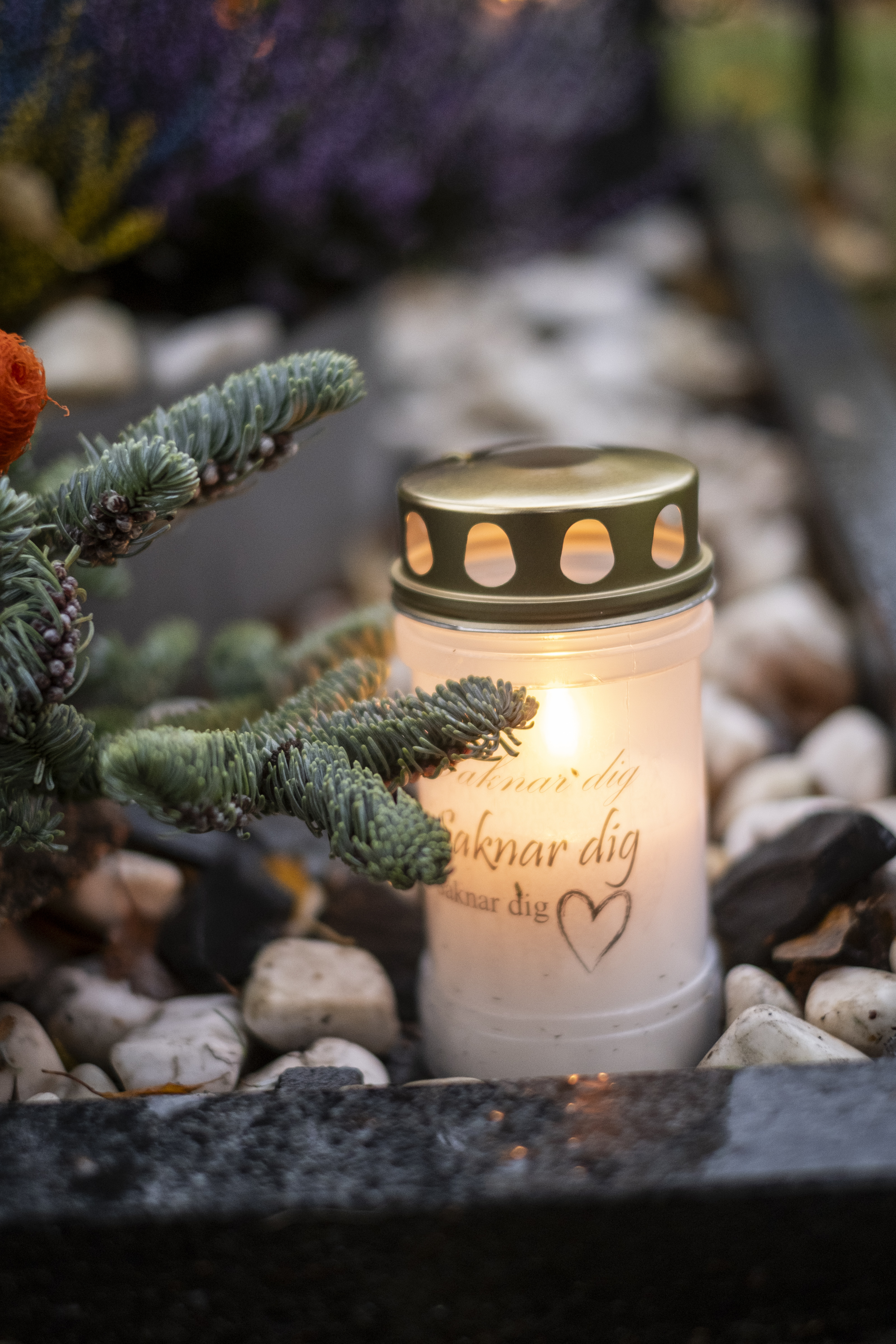 Ett gravljus lyser på en gravplats.