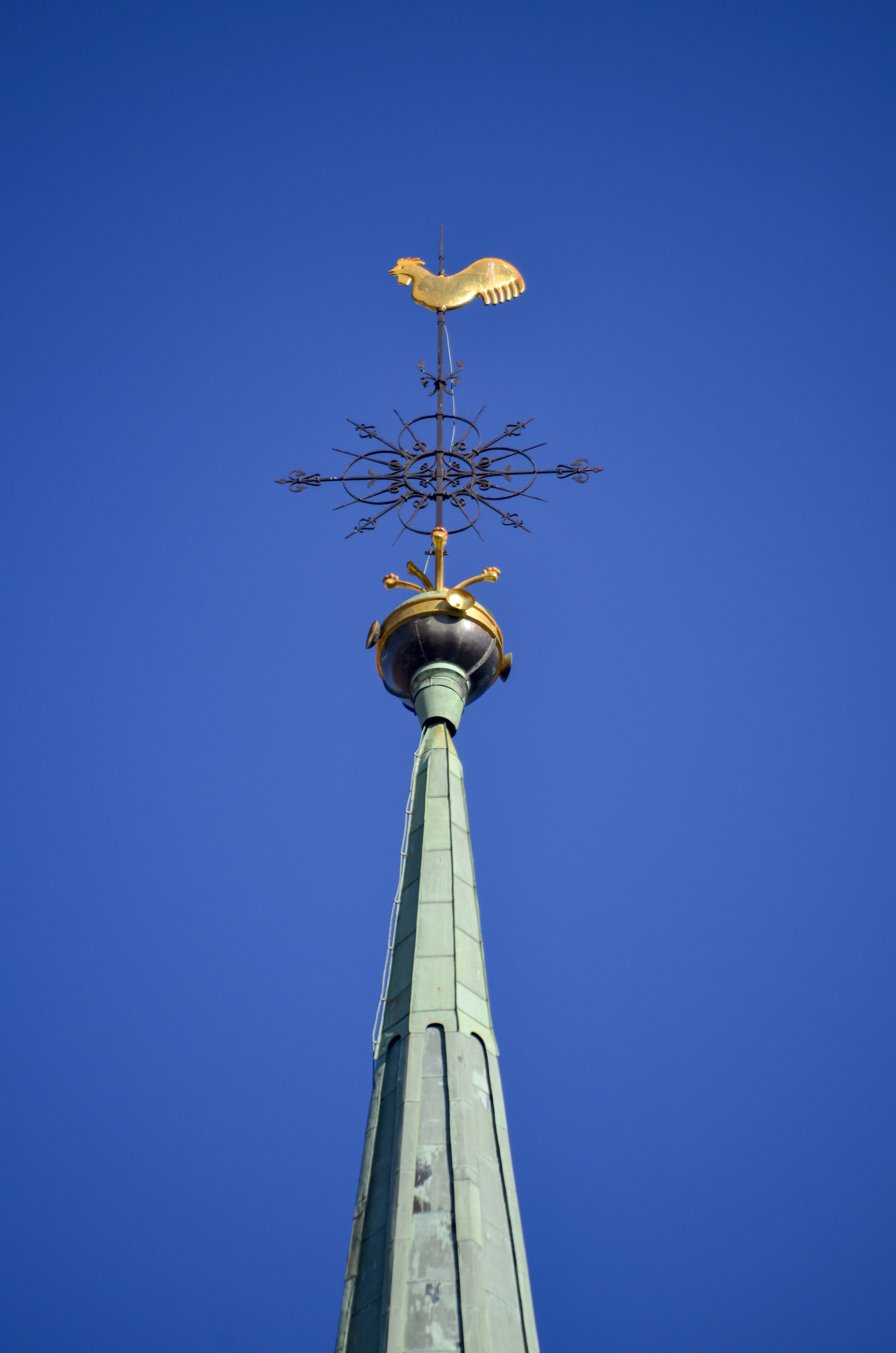 En gyllene kyrktupp på ett kyrktorn av koppar.