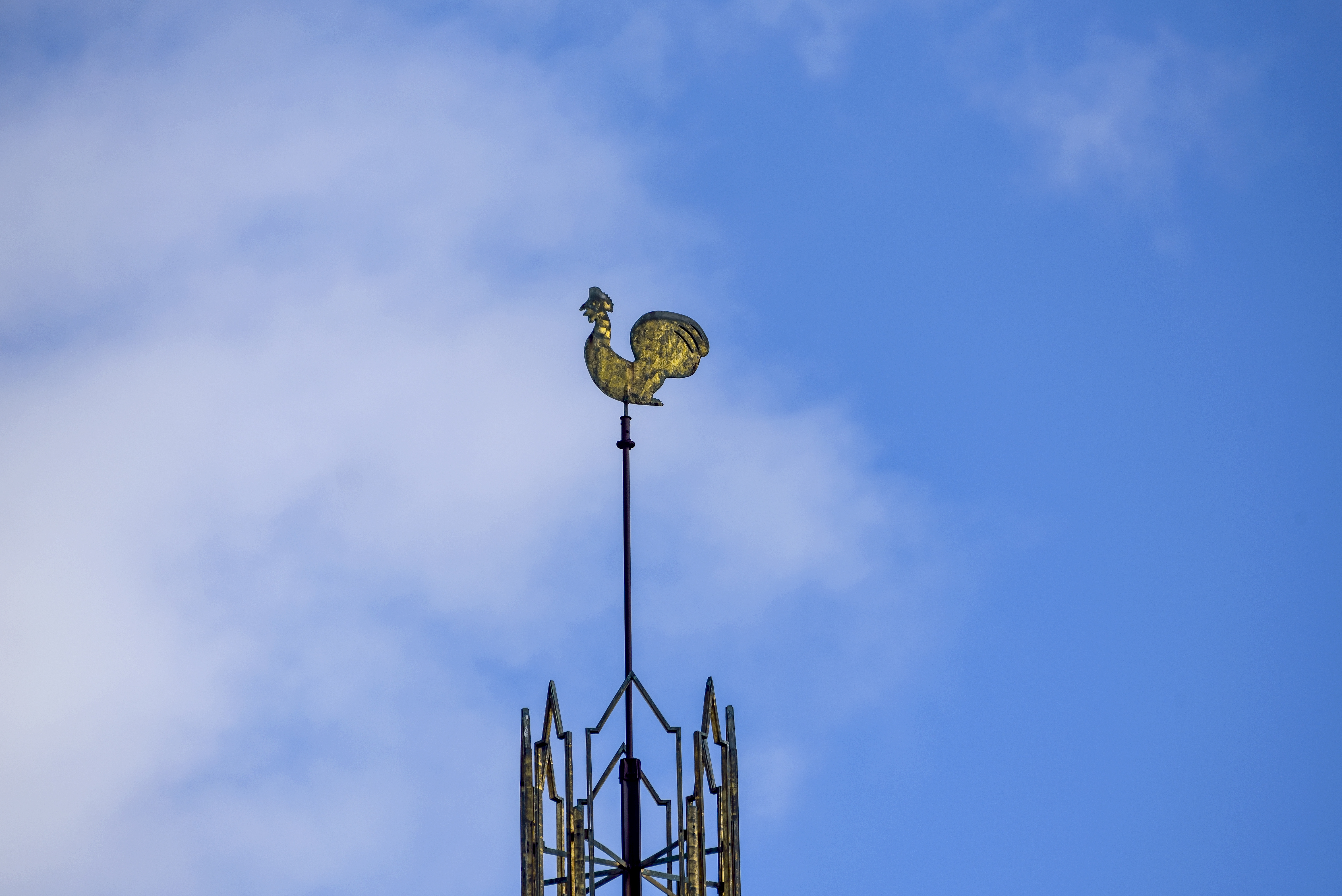 En kyrktupp mot blå himmel.