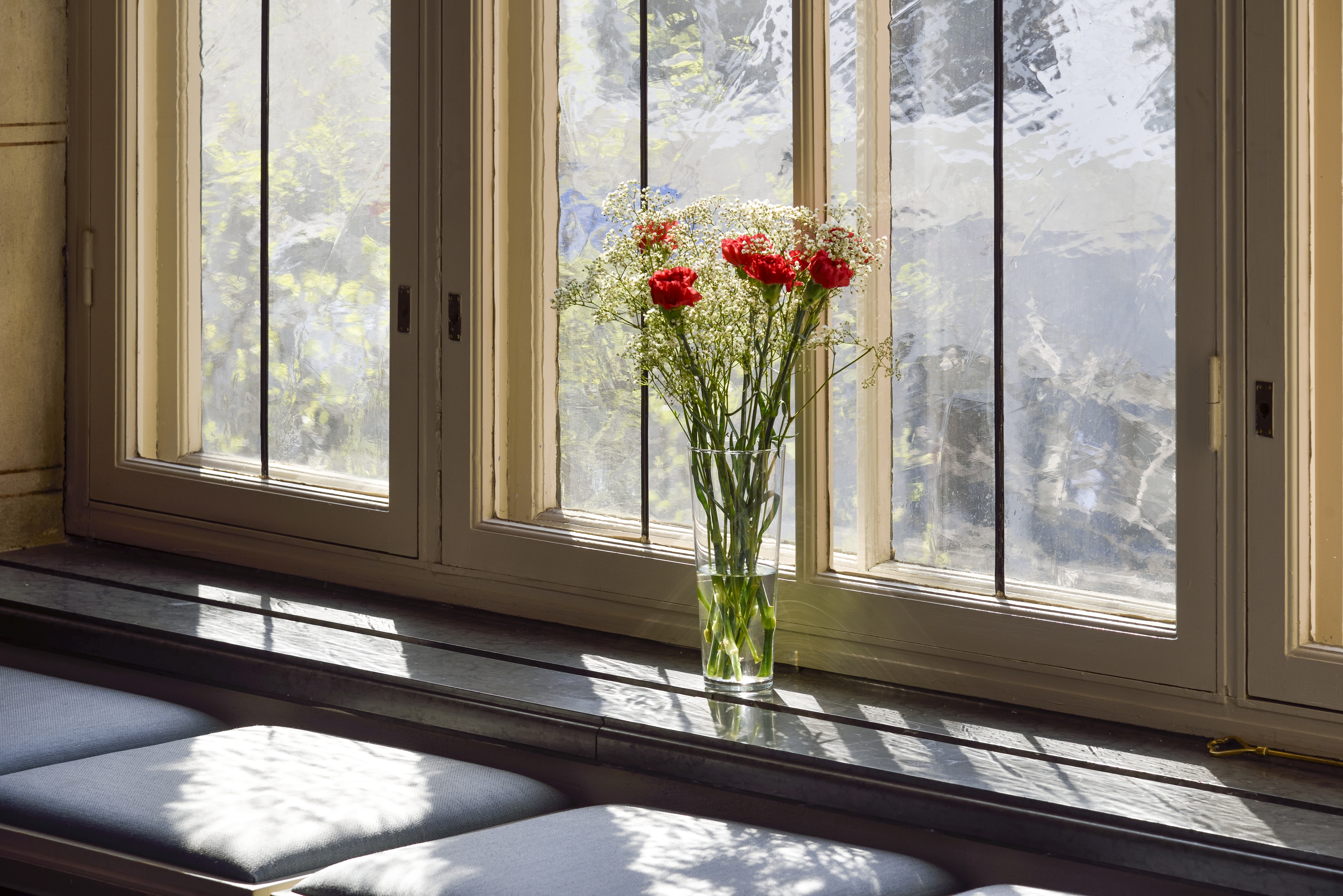 En bukett med röda rosor och brudslöja står i en vas i ett fönster.