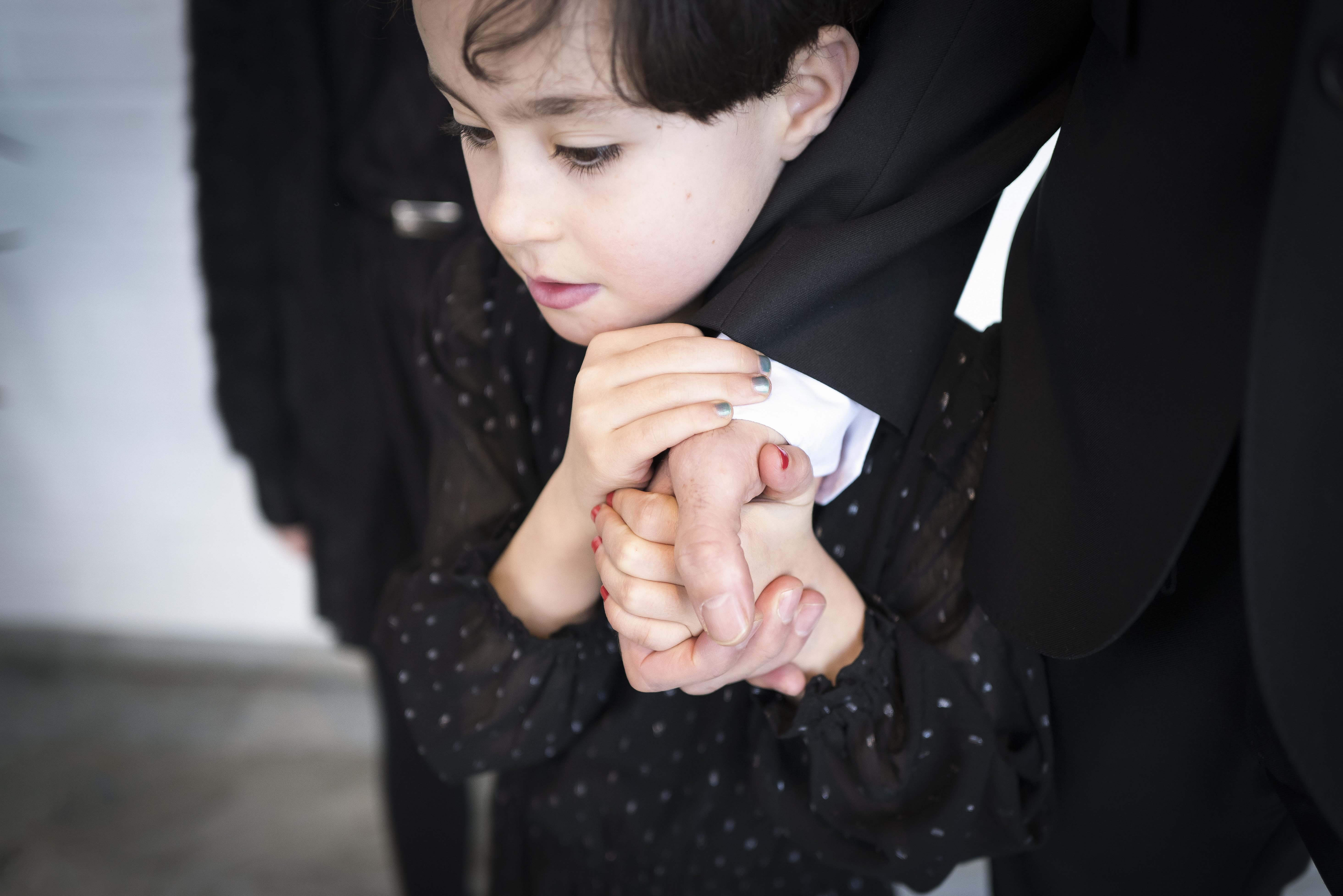 Ett barn håller en vuxens hand med båda händerna.